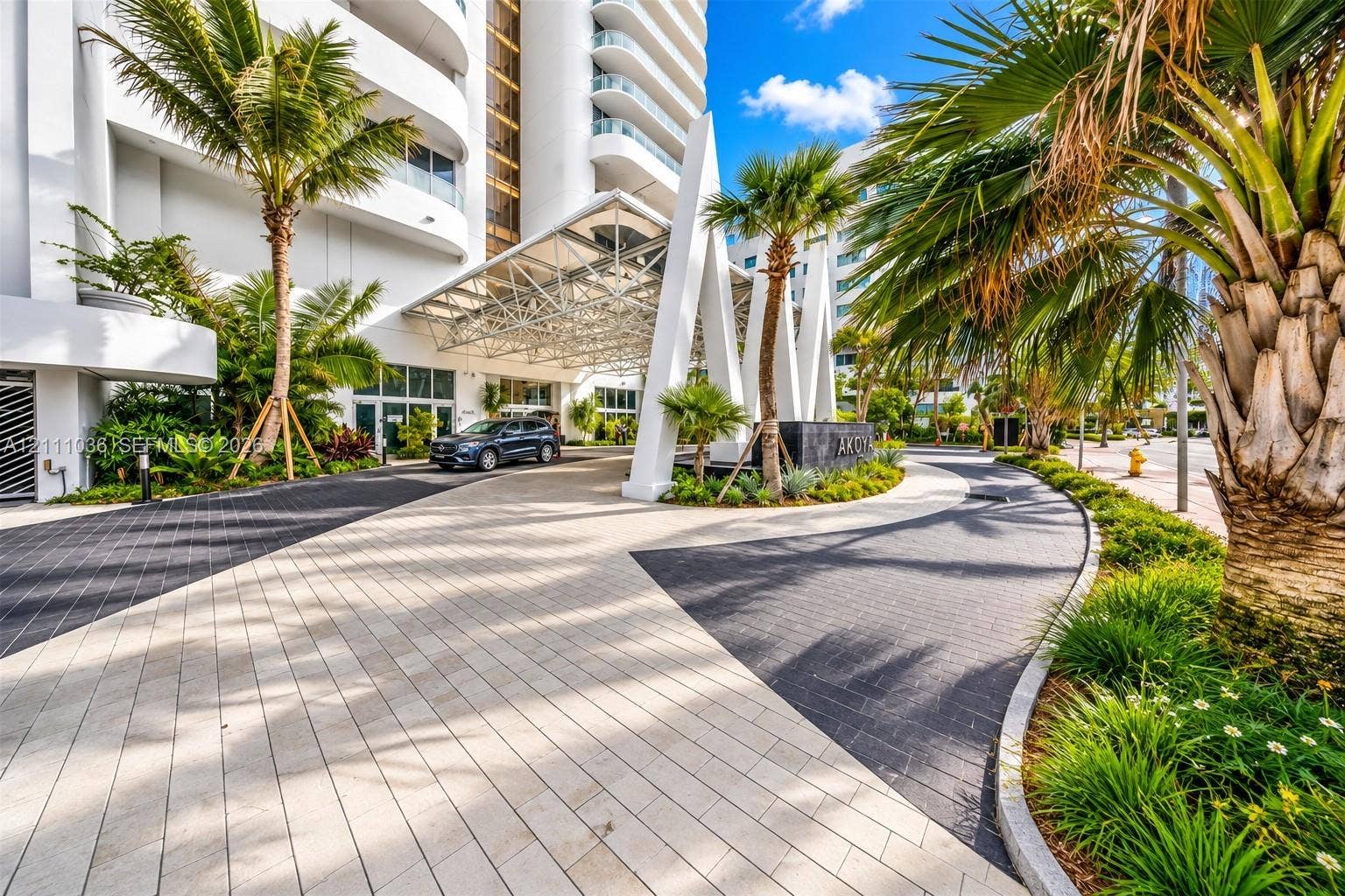 6365 Collins Avenue, #3811, Miami Beach, FL 33141 Building exterior featuring a geometric steel-frame portico, multi-toned paved driveway, and curated tropical landscaping