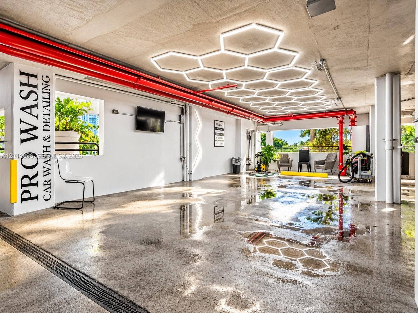 6365 Collins Avenue, #3811, Miami Beach, FL 33141 Car wash and detailing station featuring custom hexagonal overhead lighting, industrial concrete flooring, and an integrated drainage system