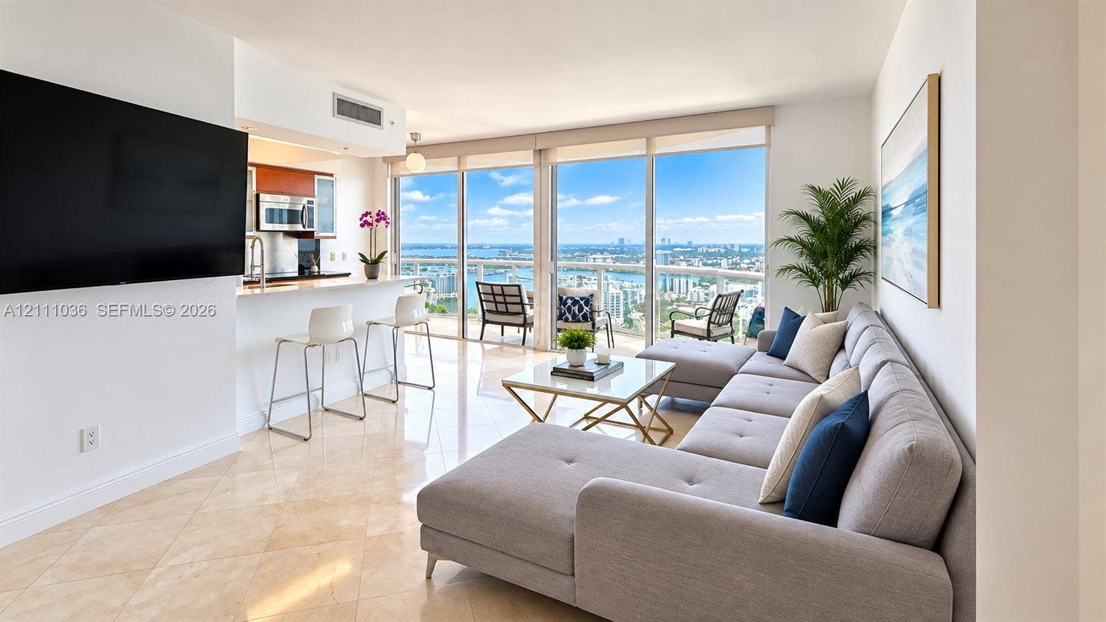 6365 Collins Avenue, #3811, Miami Beach, FL 33141 Open-concept interior featuring large-format tile flooring, floor-to-ceiling windows, an integrated kitchen breakfast bar, and a balcony with expansive urban and water scenery