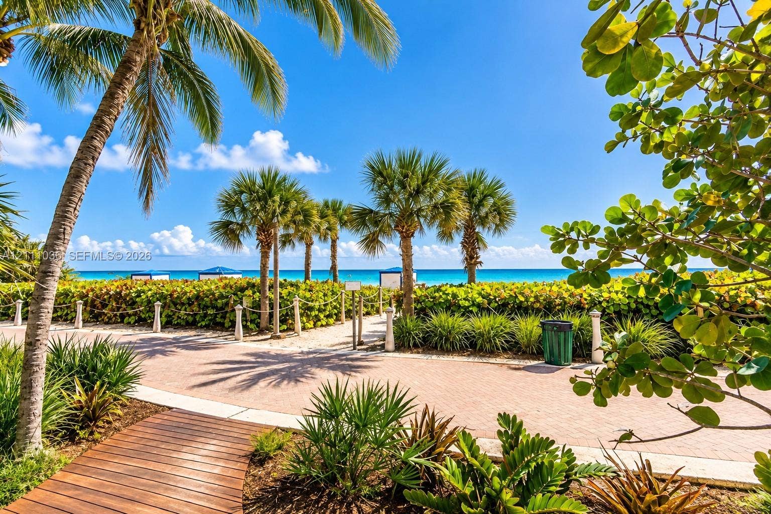 6365 Collins Avenue, #3811, Miami Beach, FL 33141 Paver walkway featuring mature palm trees, coastal landscaping, and wooden boardwalk accents