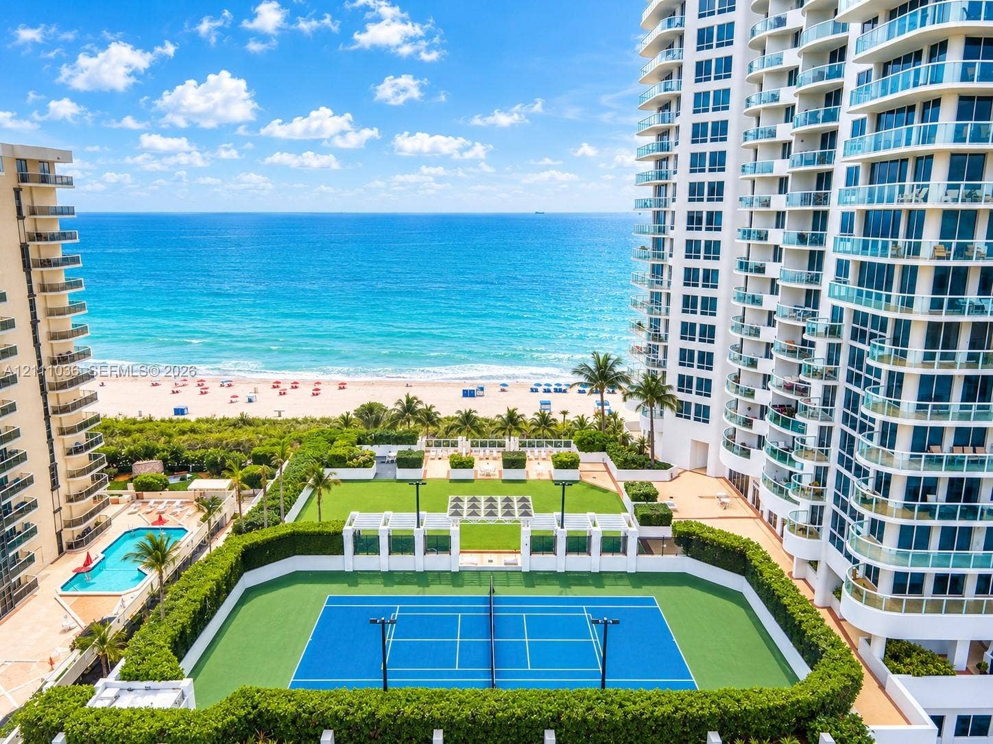 6365 Collins Avenue, #3811, Miami Beach, FL 33141 High-rise property featuring a private tennis court, outdoor swimming pool, manicured lawn area, and tiered balconies