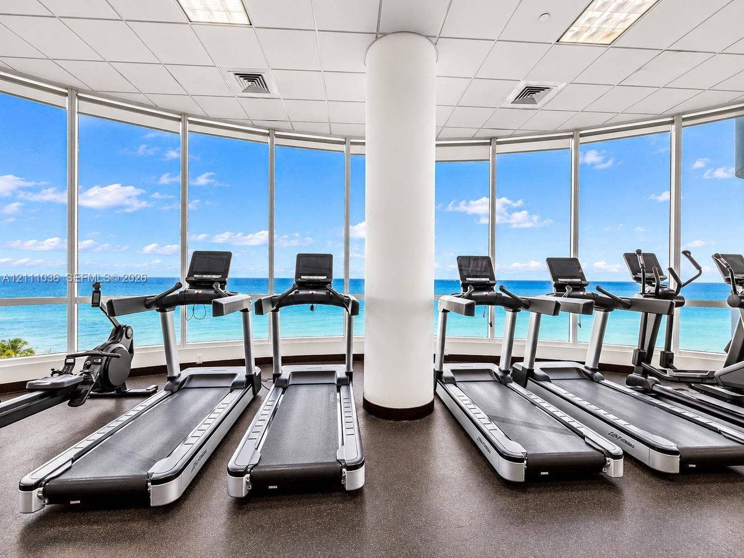 6365 Collins Avenue, #3811, Miami Beach, FL 33141 Fitness center featuring floor-to-ceiling panoramic windows, ocean horizon exposure, and a central structural column