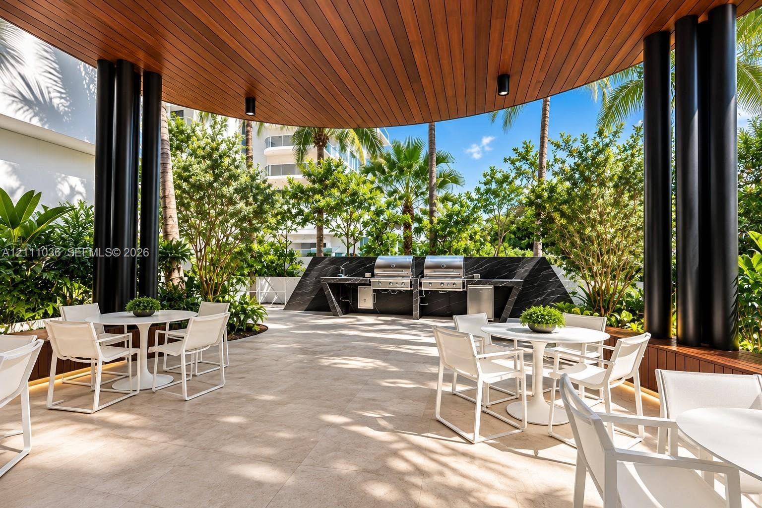 6365 Collins Avenue, #3811, Miami Beach, FL 33141 Covered outdoor kitchen featuring dual stainless steel grills, stone-finish countertops, wood-paneled ceiling, and large-format tile flooring
