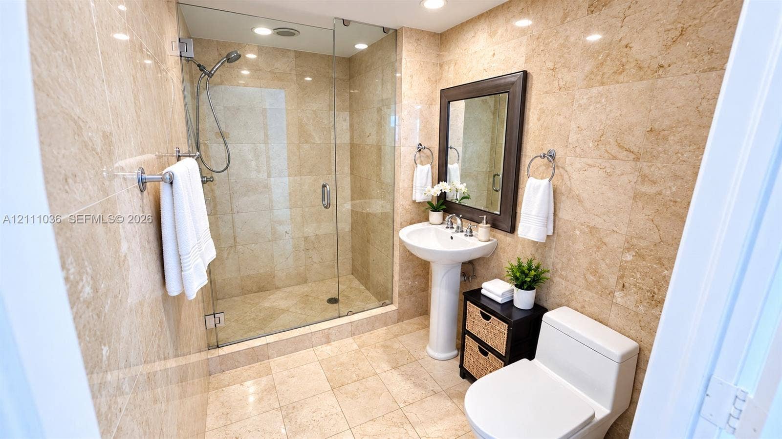 6365 Collins Avenue, #3811, Miami Beach, FL 33141 Full-height natural stone wall tiling, walk-in glass-enclosed shower, pedestal sink, and polished chrome fixtures