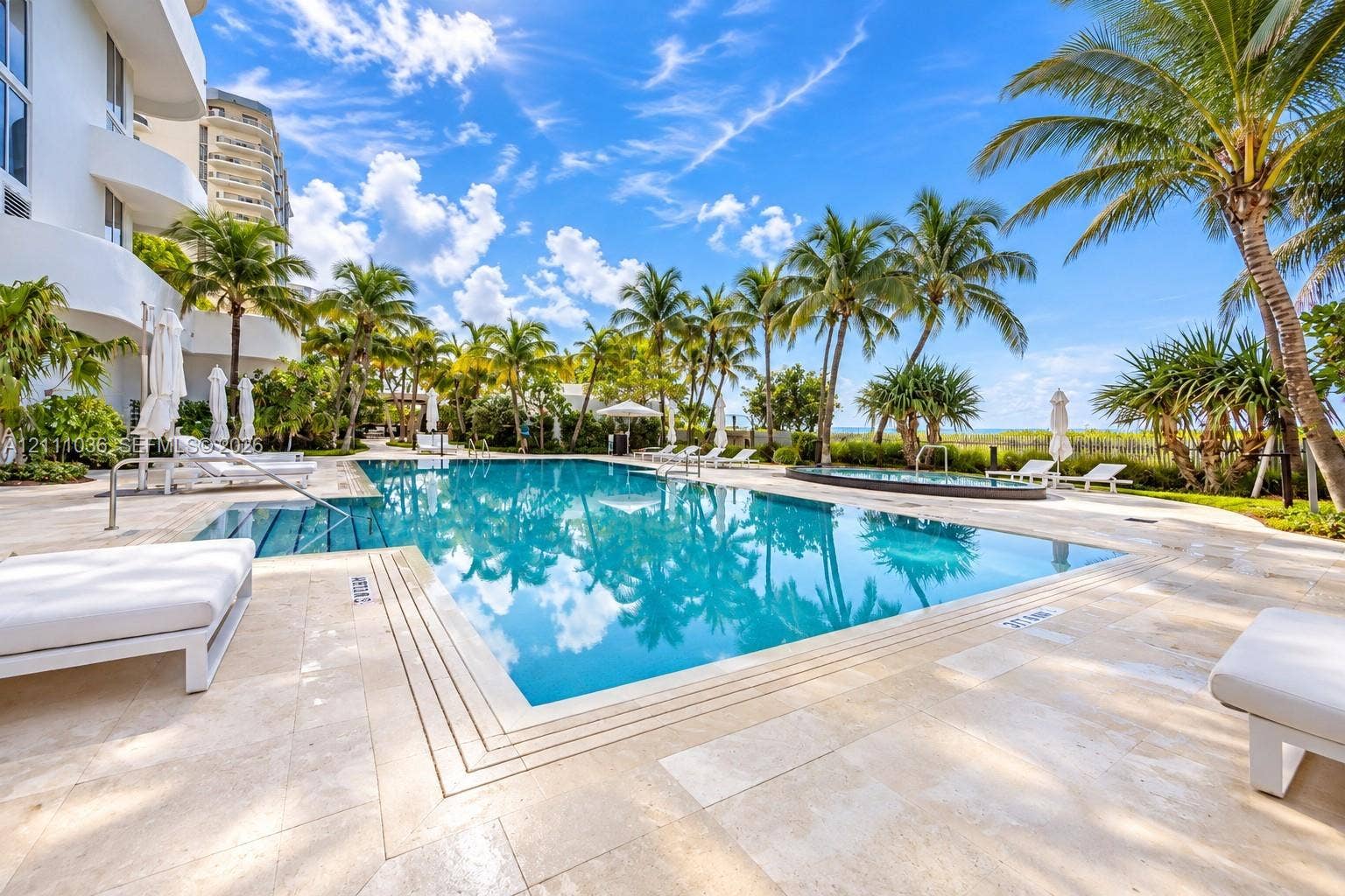 6365 Collins Avenue, #3811, Miami Beach, FL 33141 Swimming pool with stone-tiled deck, integrated spa, and surrounding palm trees