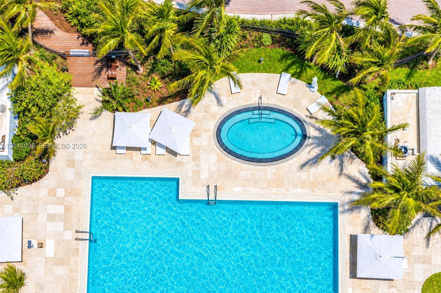 6365 Collins Avenue, #3811, Miami Beach, FL 33141 Aerial perspective of an outdoor space featuring a rectangular swimming pool, an oval-shaped spa, stone-paver decking, and mature palm trees