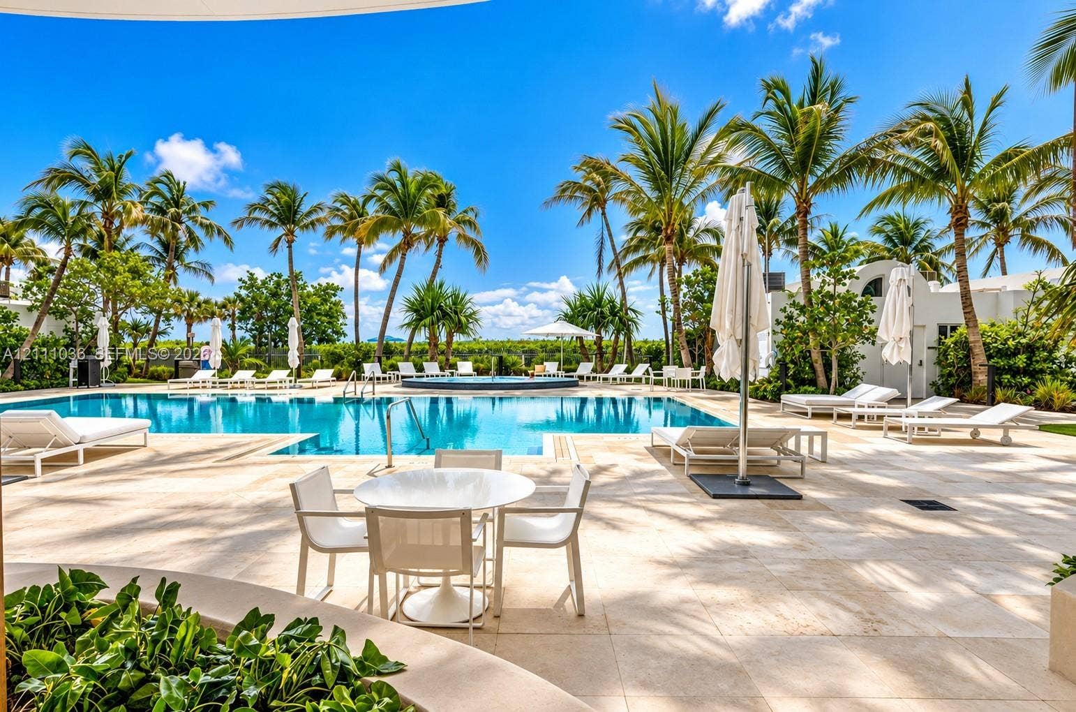 6365 Collins Avenue, #3811, Miami Beach, FL 33141 Swimming pool with integrated spa, expansive stone-paved deck, and mature palm trees