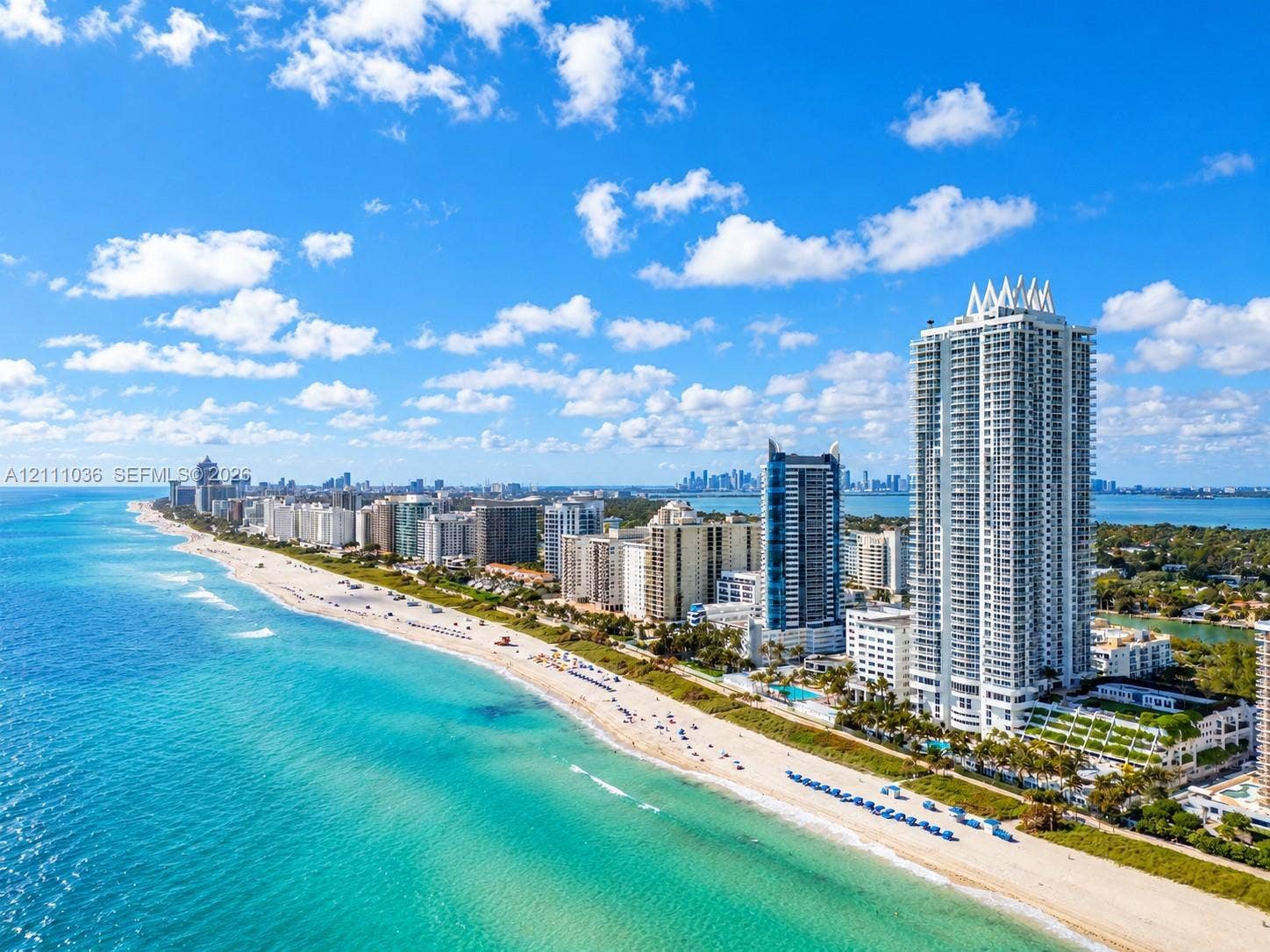 6365 Collins Avenue, #3811, Miami Beach, FL 33141 High-rise coastal tower featuring a white concrete facade, expansive glass balconies, direct beachfront access, and a multi-level terraced podium