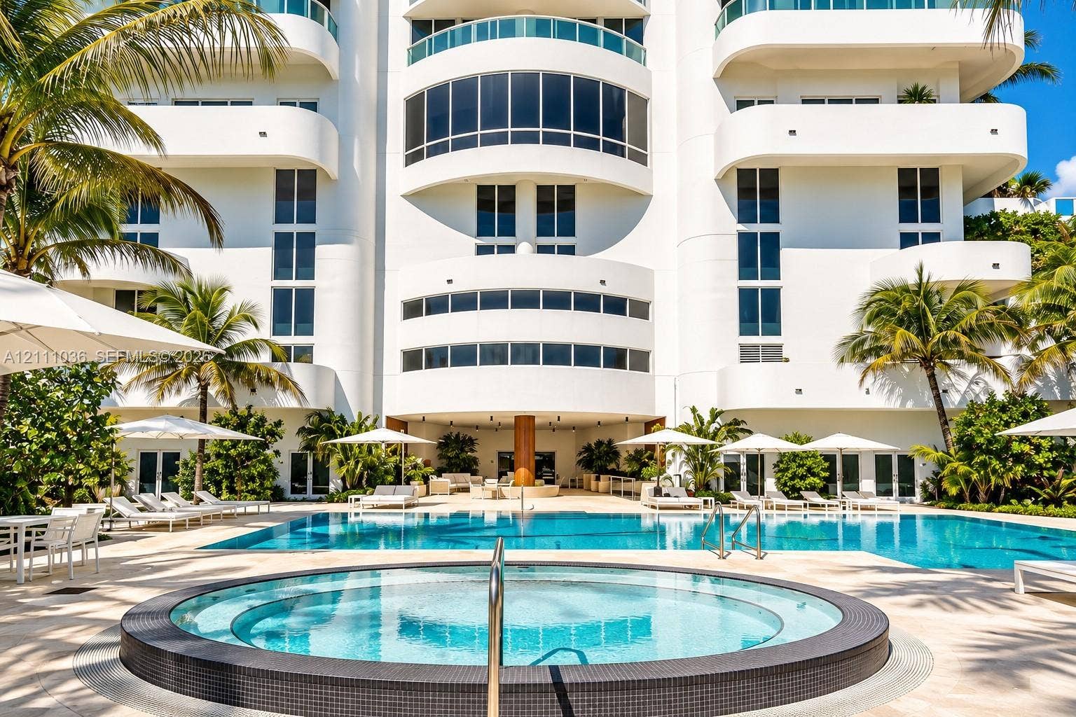 6365 Collins Avenue, #3811, Miami Beach, FL 33141 Multi-story exterior featuring curved balconies, floor-to-ceiling windows, a circular spa with tiled surround, a sprawling swimming pool, and stone paver decking