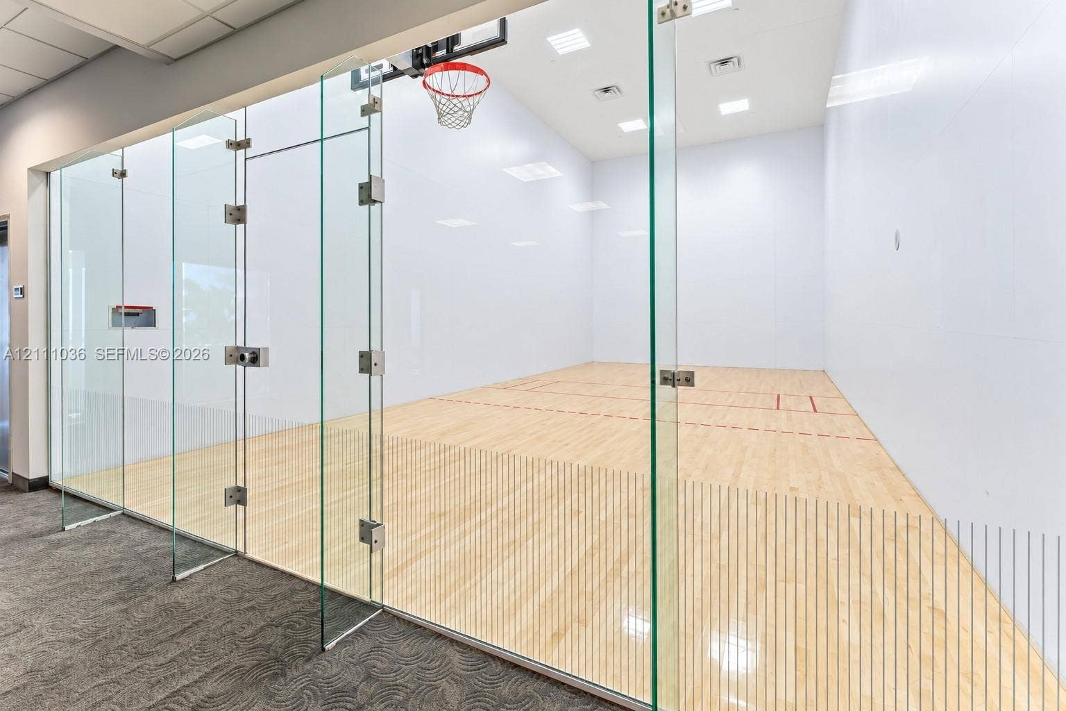 6365 Collins Avenue, #3811, Miami Beach, FL 33141 Recreational court featuring frameless glass wall enclosures, high-contrast wood-finish flooring, recessed ceiling lighting, and a built-in basketball hoop