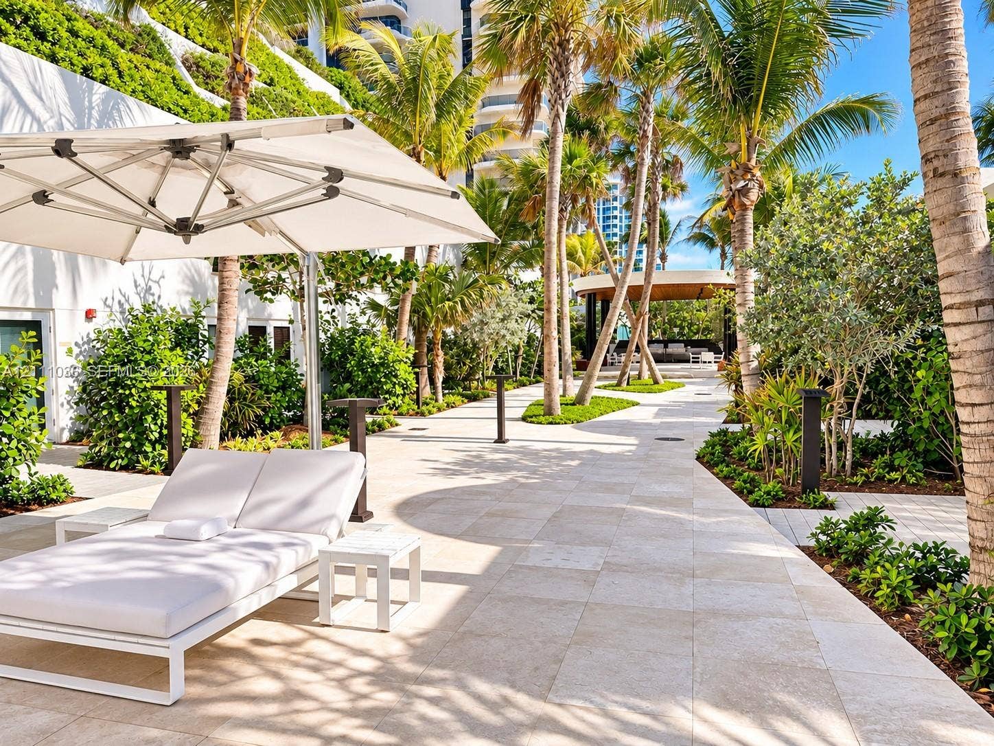 6365 Collins Avenue, #3811, Miami Beach, FL 33141 Outdoor patio featuring natural stone paving, mature palm trees, tiered tropical landscaping, and a covered pavilion