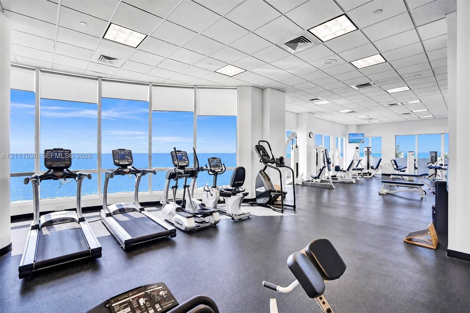 6365 Collins Avenue, #3811, Miami Beach, FL 33141 Fitness center featuring expansive floor-to-ceiling windows, panoramic ocean scenery, durable rubber flooring, and a suspended drop-tile ceiling