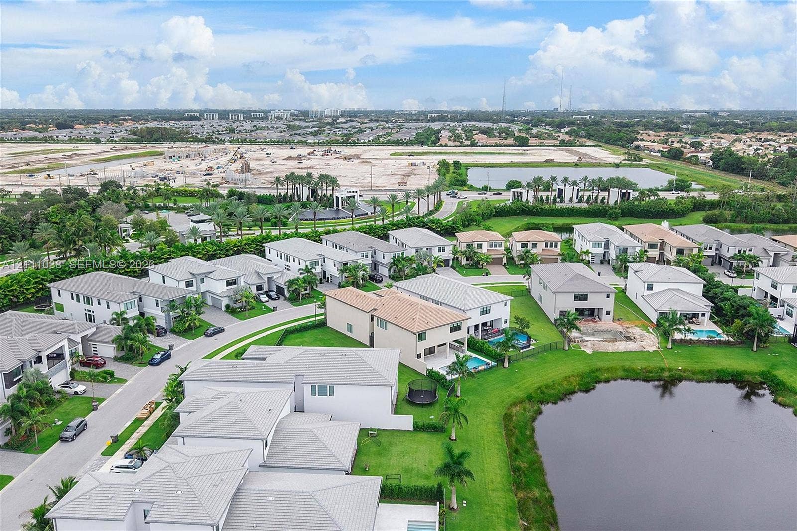 Aerial perspective featuring multi-story residential structures with neutral-toned stucco exteriors and pitched roofs, situated on landscaped lots with private swimming pools and water frontage