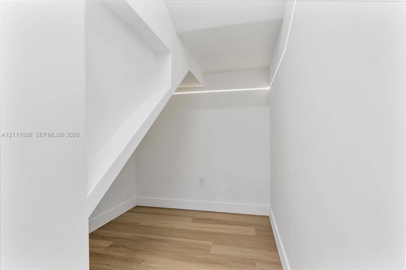 Architectural alcove featuring wood-finish flooring, smooth white walls, and integrated linear LED strip lighting