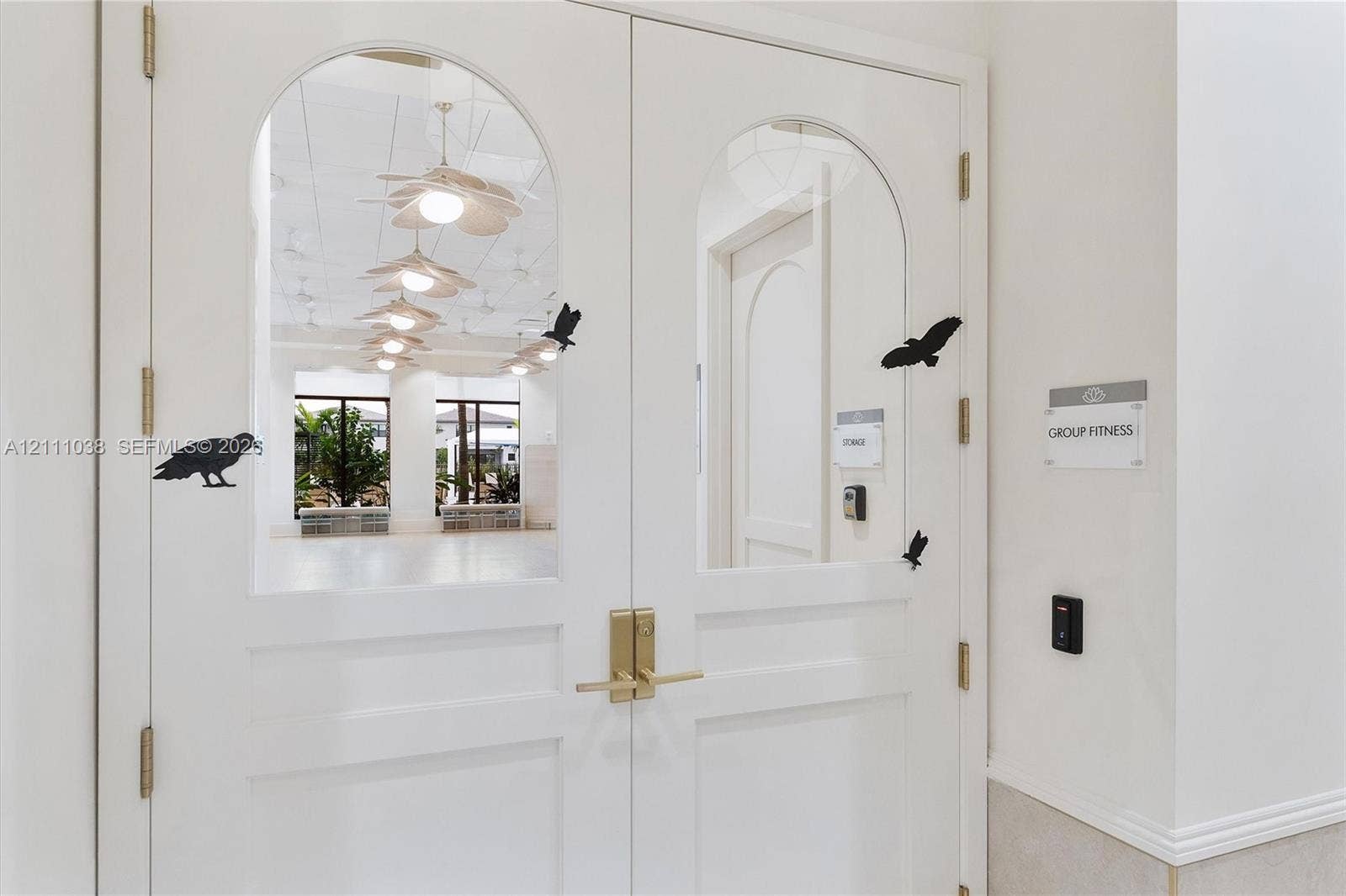 Double doors featuring arched glass panels, brass-finish lever hardware, and electronic keycard access entry