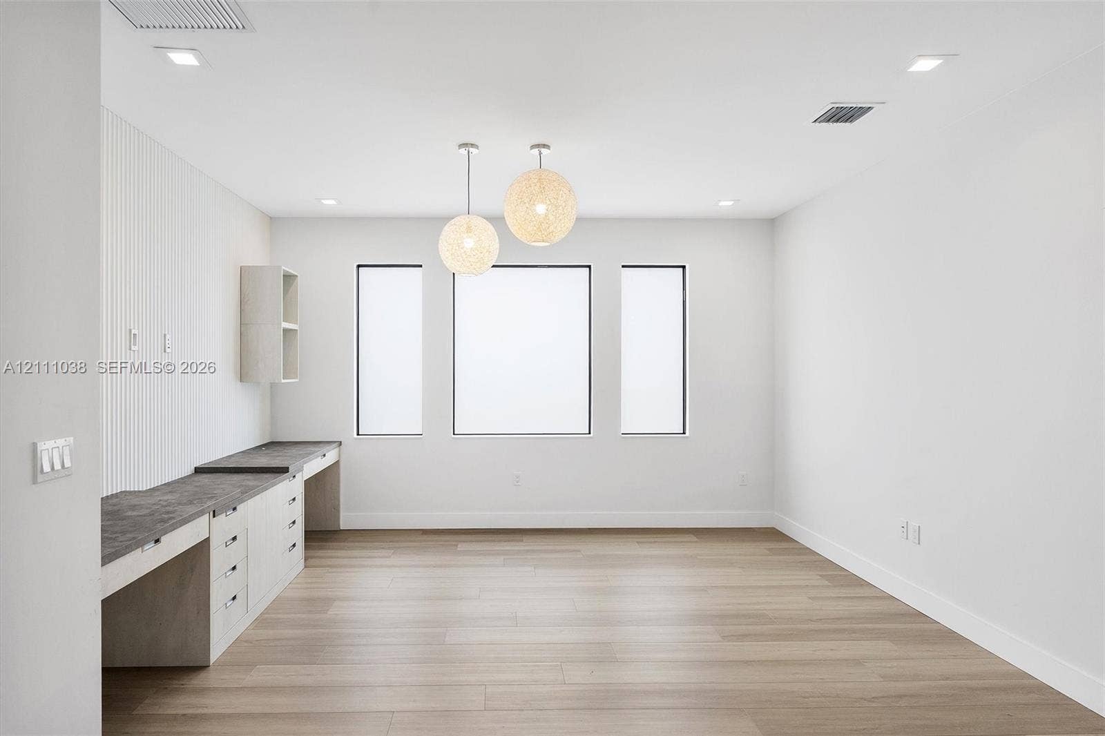 Built-in workstation featuring stone-finish countertops, shaker-style cabinetry, wood-finish flooring, recessed lighting, and textured wall paneling