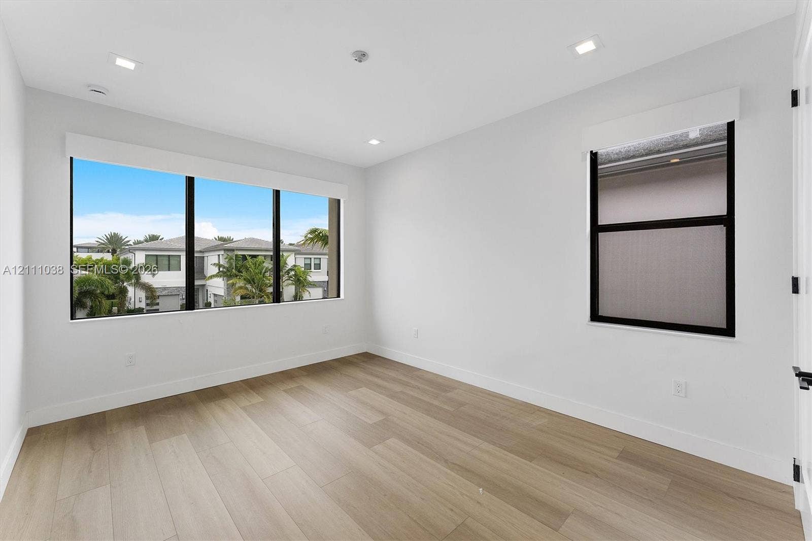 Neutral-toned interior featuring wood-finish flooring, recessed lighting, and large windows with black frames