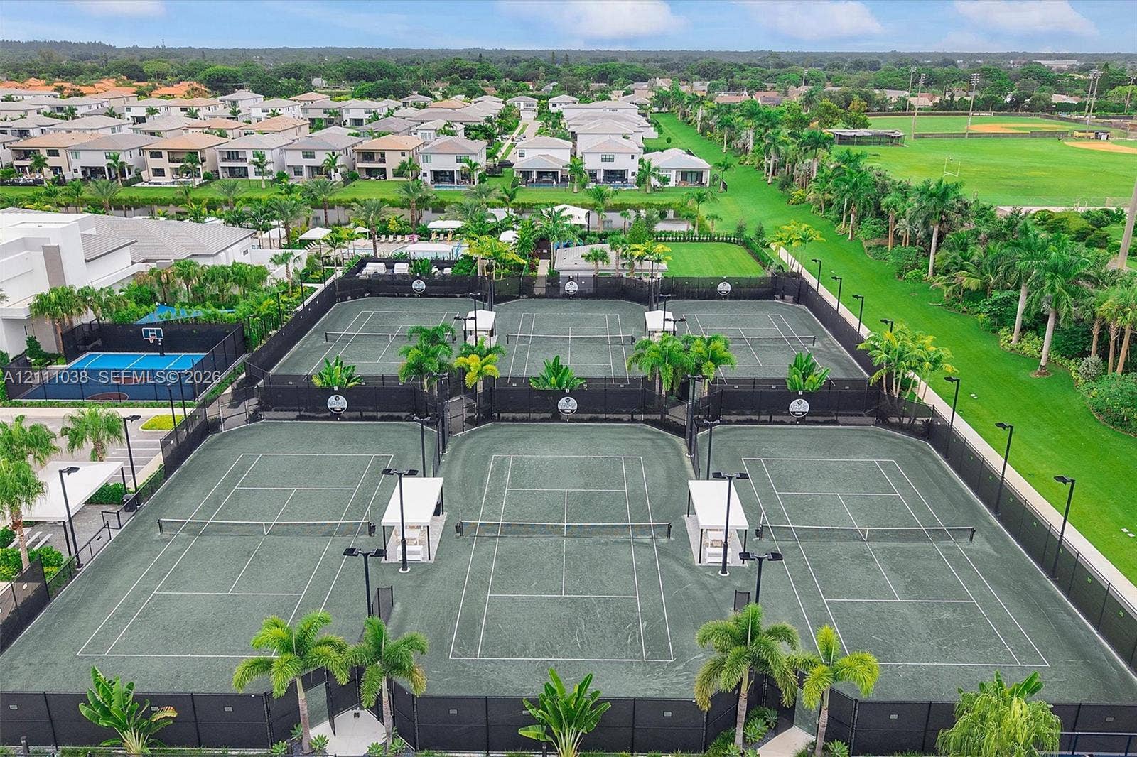 Multi-court facility featuring hard-surface tennis courts, dedicated pickleball court, and outdoor lighting fixtures