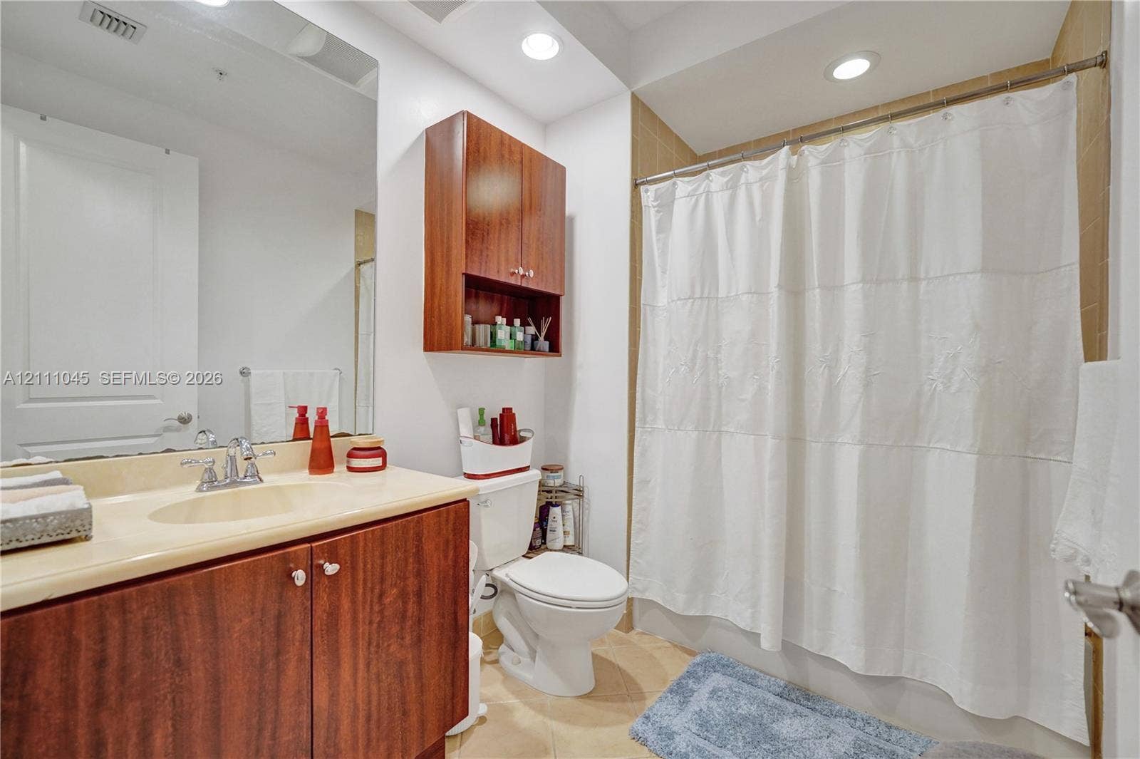 2901 NW 126th Avenue, #2-225, Sunrise, FL 33323 Bathroom featuring wood-finish cabinetry, a seamless countertop with an integrated sink, a wall-mounted storage cabinet, and recessed ceiling lighting