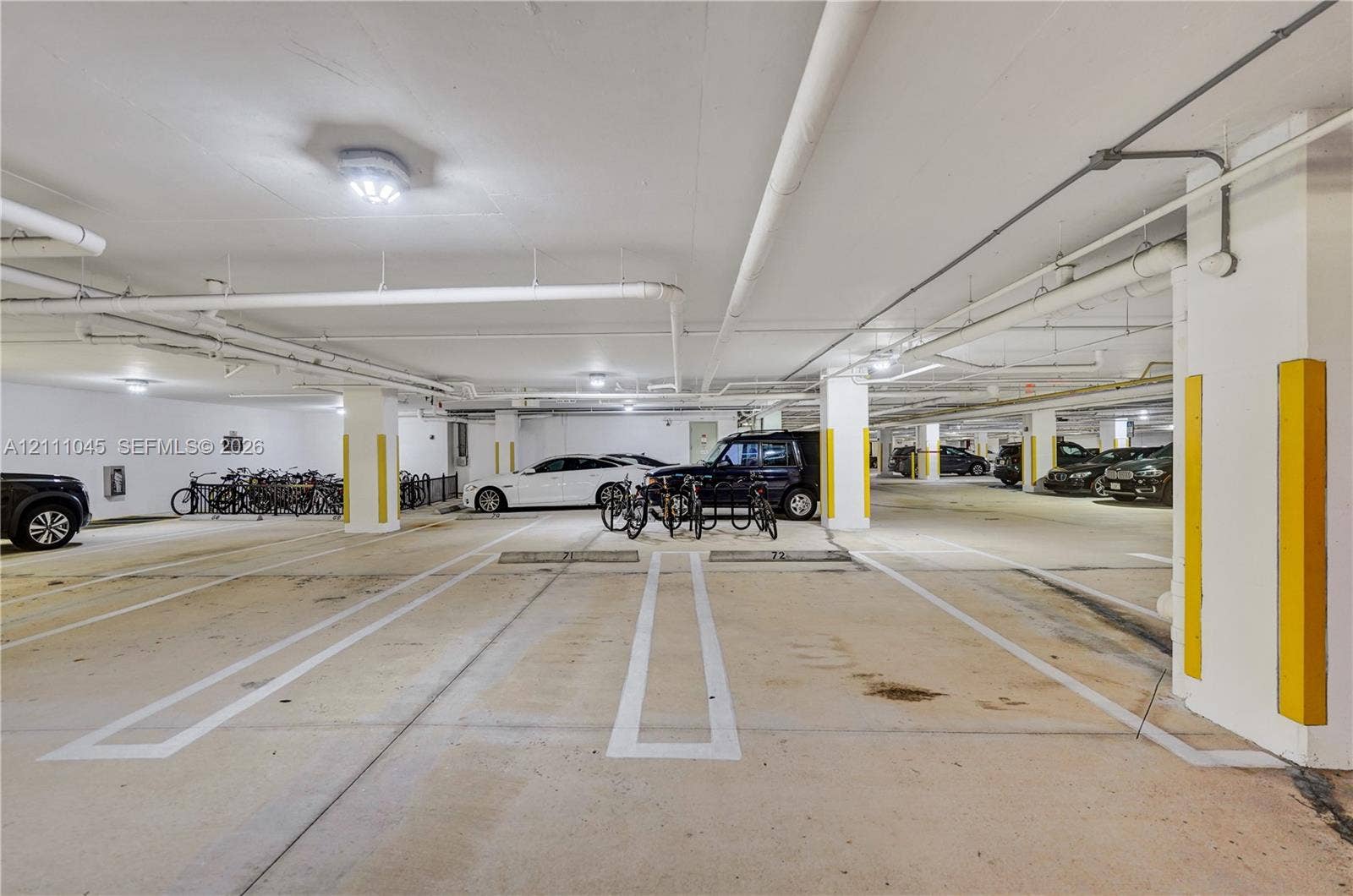 2901 NW 126th Avenue, #2-225, Sunrise, FL 33323 Covered parking garage featuring concrete flooring, designated stalls with painted line markings, structural columns, and integrated bicycle racks