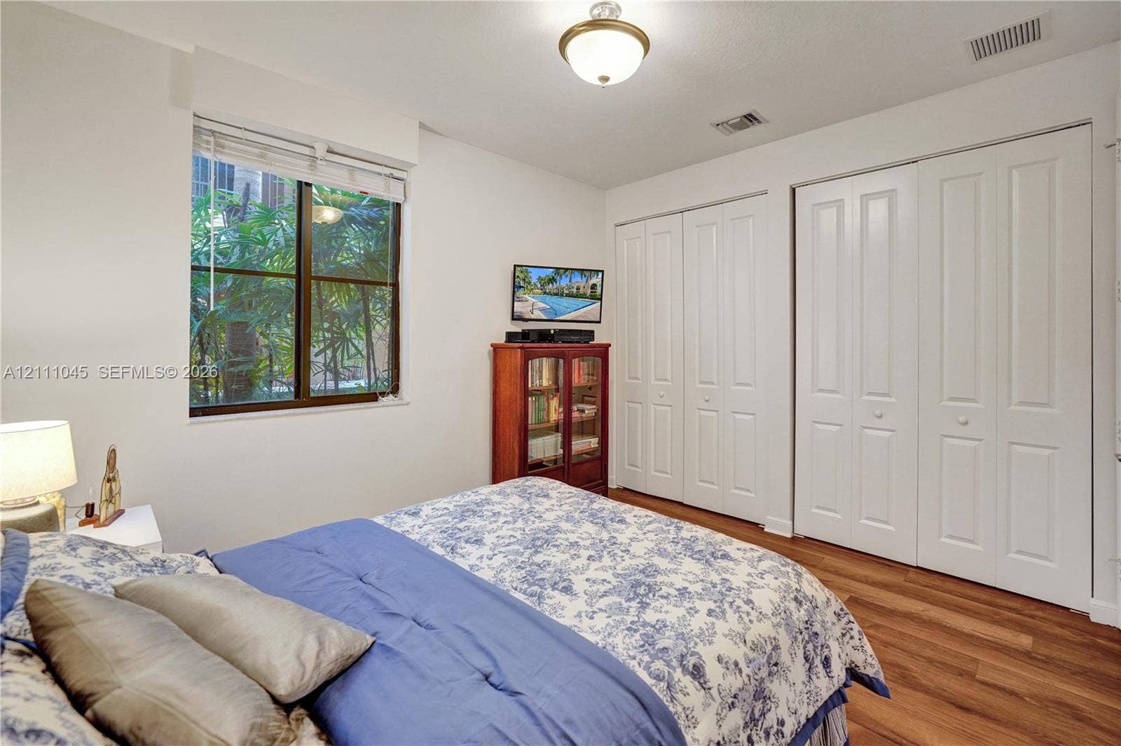 2901 NW 126th Avenue, #2-225, Sunrise, FL 33323 Bedroom featuring wood-finish flooring, dual bi-fold door closets, a large window, and a central ceiling-mounted light fixture