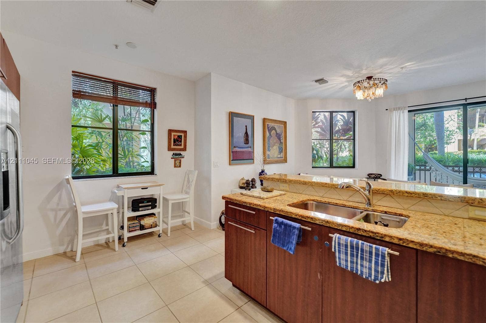 2901 NW 126th Avenue, #2-225, Sunrise, FL 33323 Kitchen featuring a breakfast bar with stone-surfaced countertops, a stainless steel dual-basin undermount sink, dark-finish cabinetry, and ceramic tile flooring