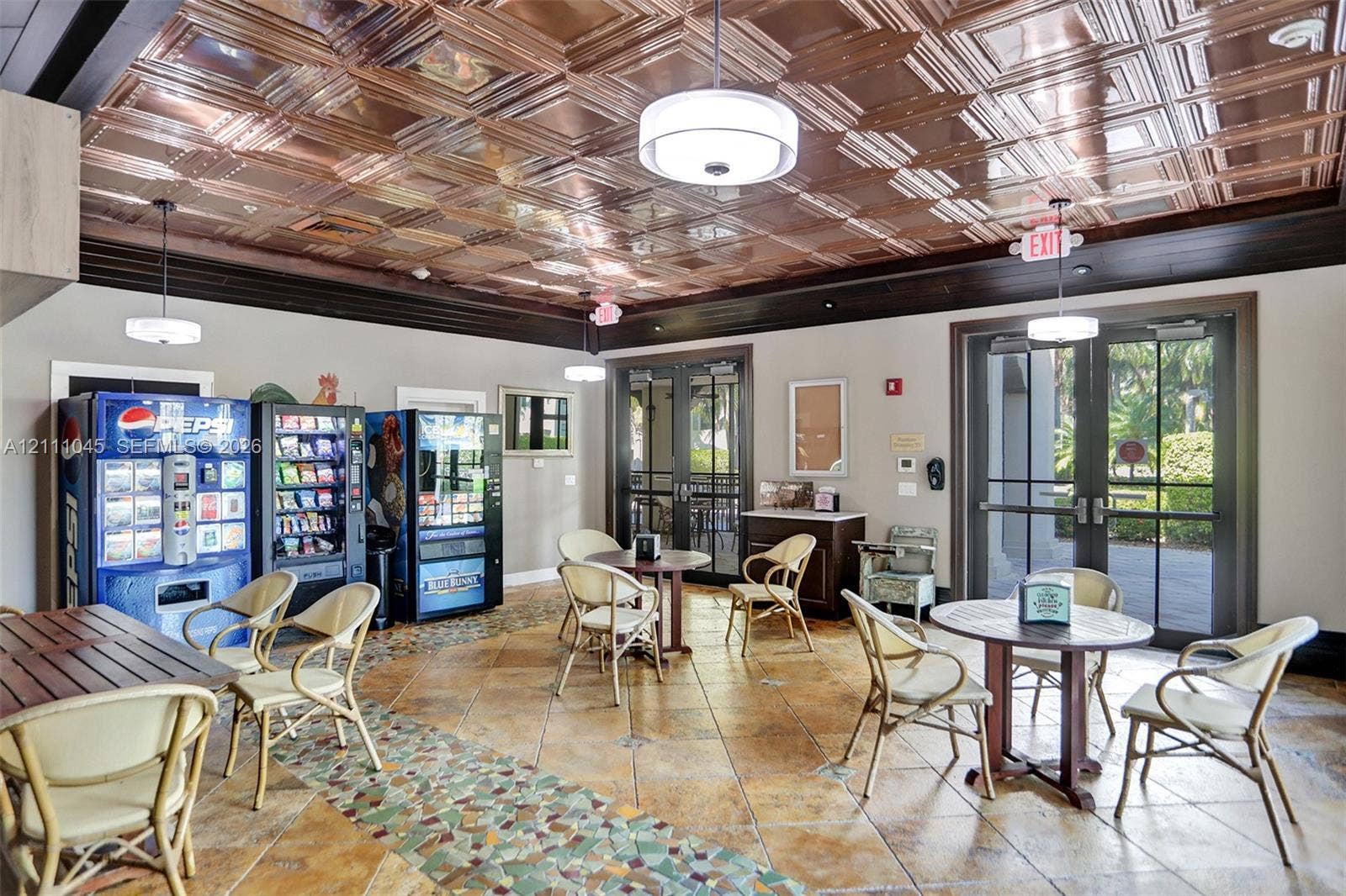 2901 NW 126th Avenue, #2-225, Sunrise, FL 33323 Interior space featuring a decorative copper-toned coffered ceiling, tile flooring with mosaic accent inlay, dual sets of glass-paned double doors, and crown molding
