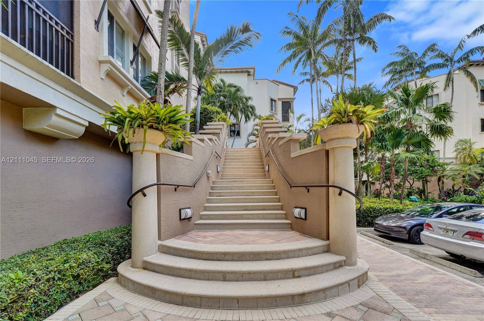 2901 NW 126th Avenue, #2-225, Sunrise, FL 33323 Exterior staircase featuring stone treads, stucco-finished retaining walls, decorative column accents topped with planters, and metal handrails