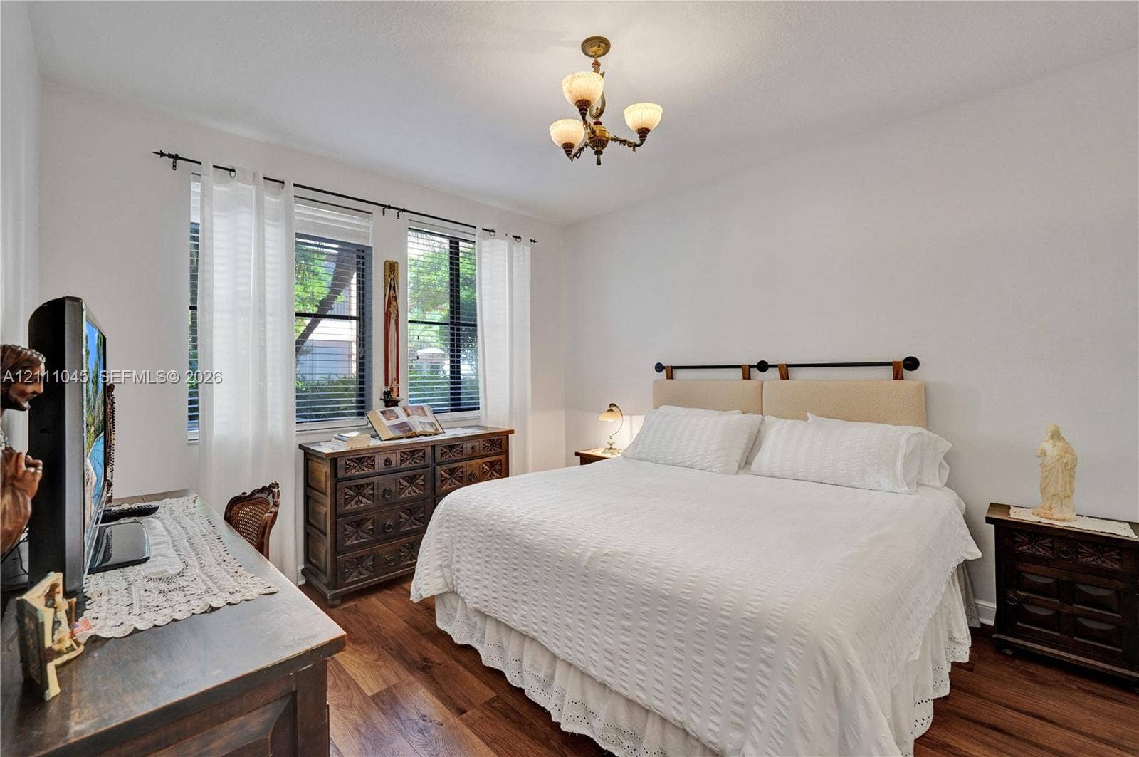 2901 NW 126th Avenue, #2-225, Sunrise, FL 33323 Bedroom featuring wood-finish flooring, dual windows with blinds, and a multi-arm chandelier