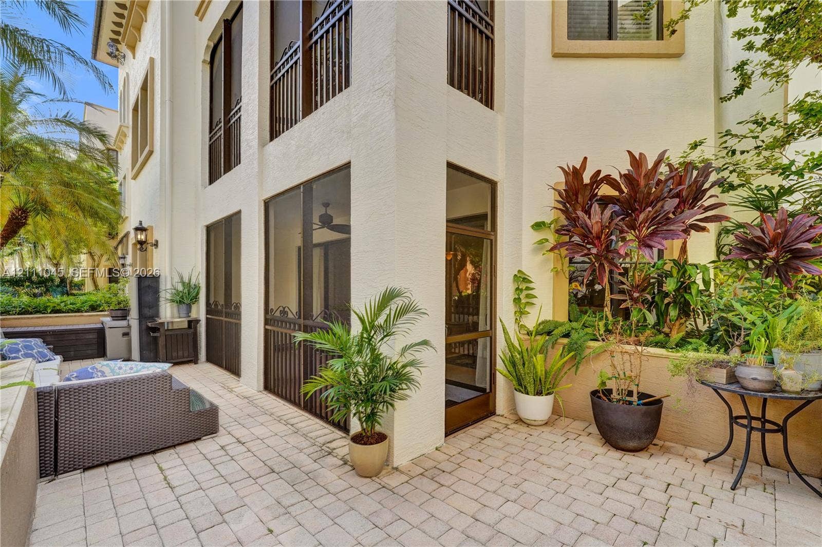 2901 NW 126th Avenue, #2-225, Sunrise, FL 33323 Stucco exterior featuring multiple levels, paved stone patio, screened enclosure, decorative metal railings, and attached exterior lighting