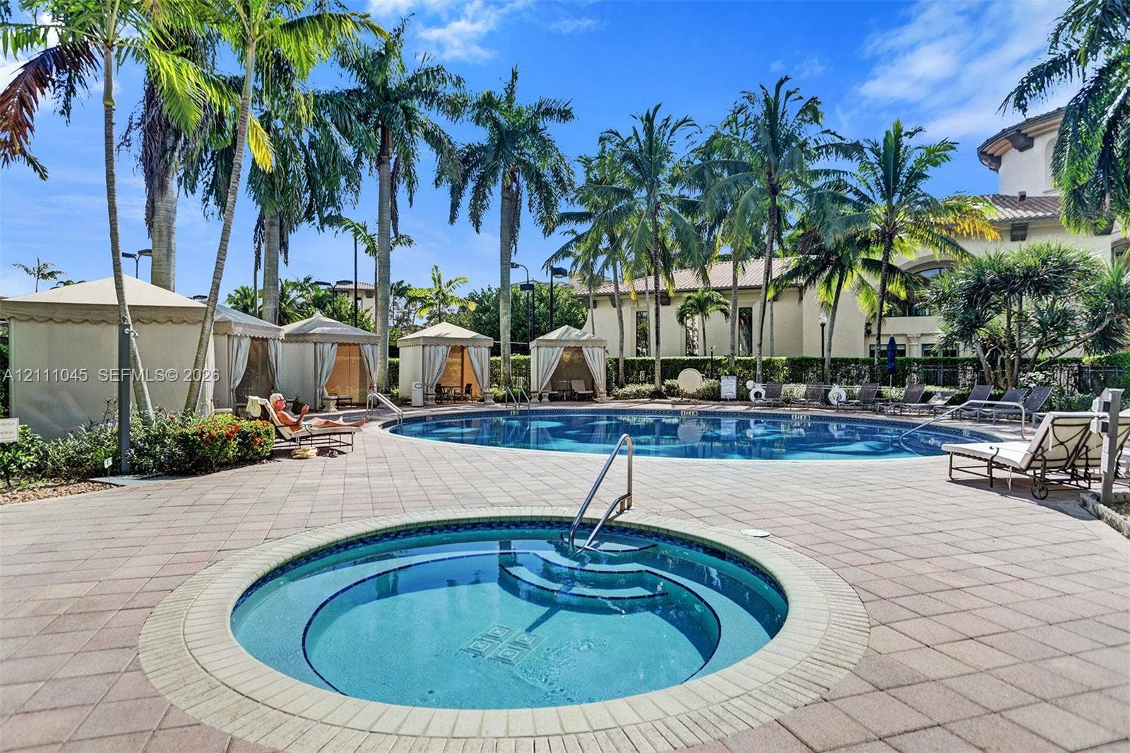 2901 NW 126th Avenue, #2-225, Sunrise, FL 33323 Swimming pool and circular spa surrounded by paver patio, multiple poolside cabanas, and mature palm trees