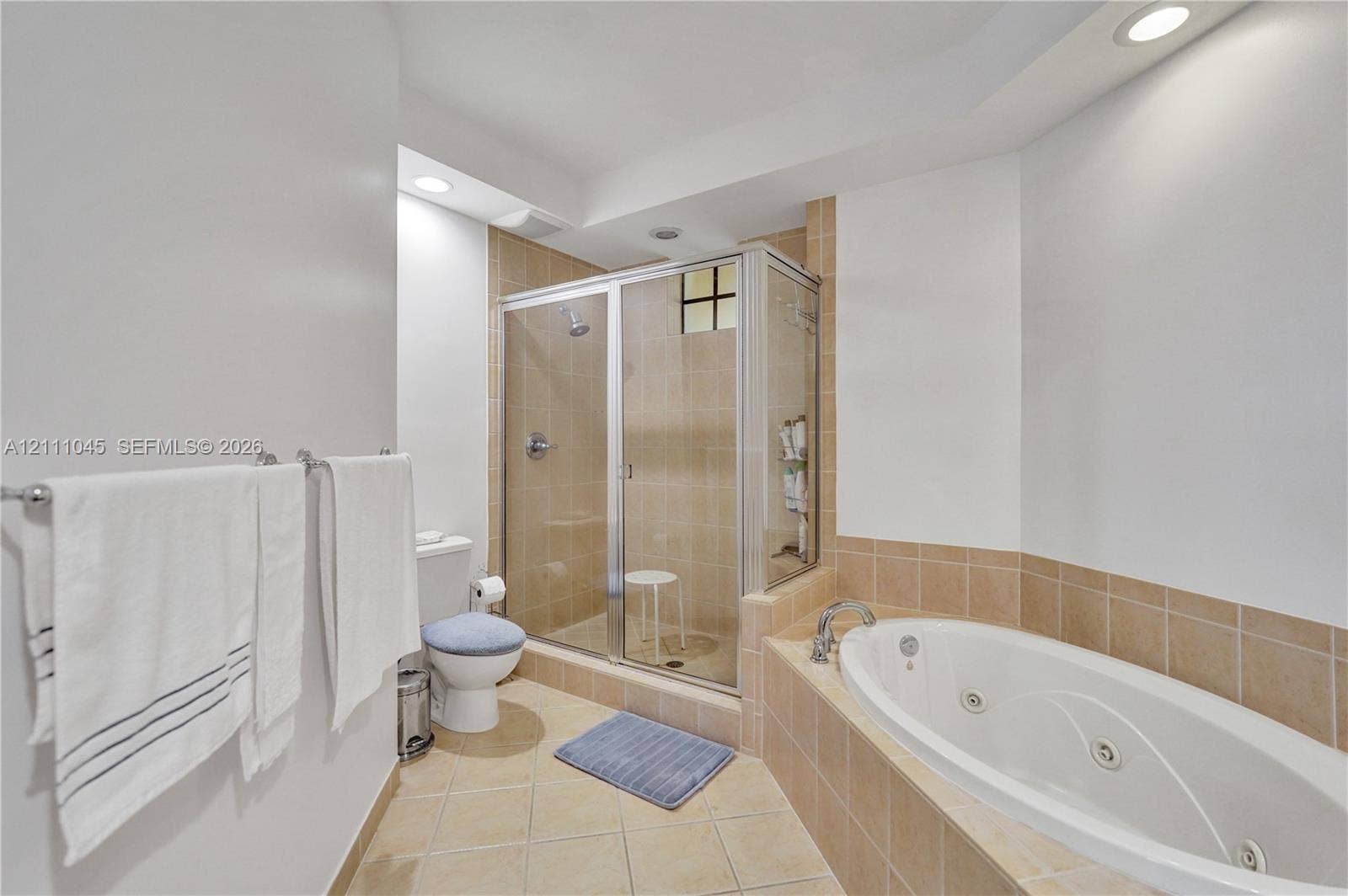 2901 NW 126th Avenue, #2-225, Sunrise, FL 33323 Bathroom featuring a jetted soaking tub, tiled shower enclosure with metal-framed glass door, and neutral tile flooring