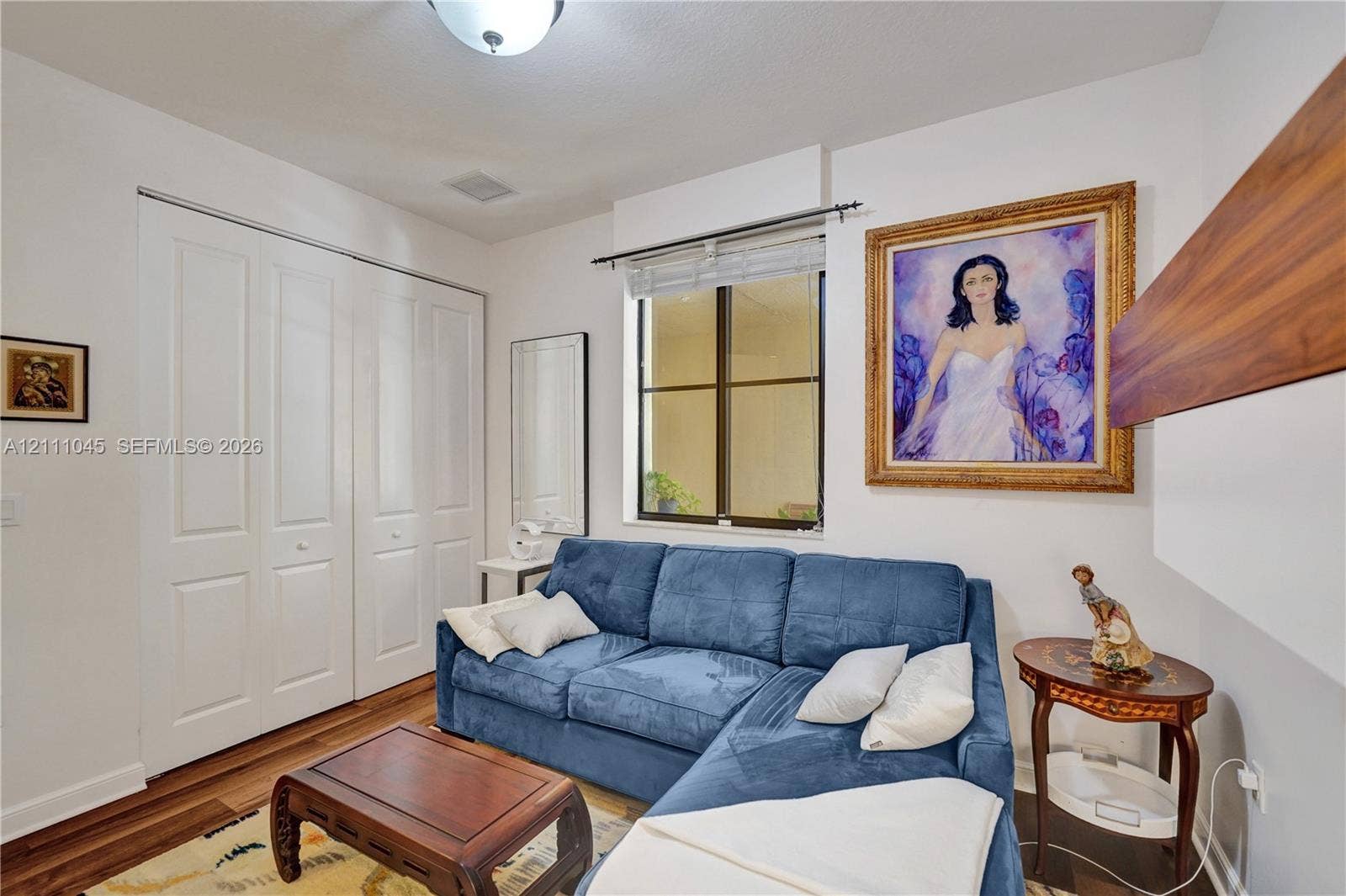2901 NW 126th Avenue, #2-225, Sunrise, FL 33323 Room featuring wood-finish flooring, dual-panel closet doors, a single-hung window with a metal frame, and a flush-mount ceiling light fixture