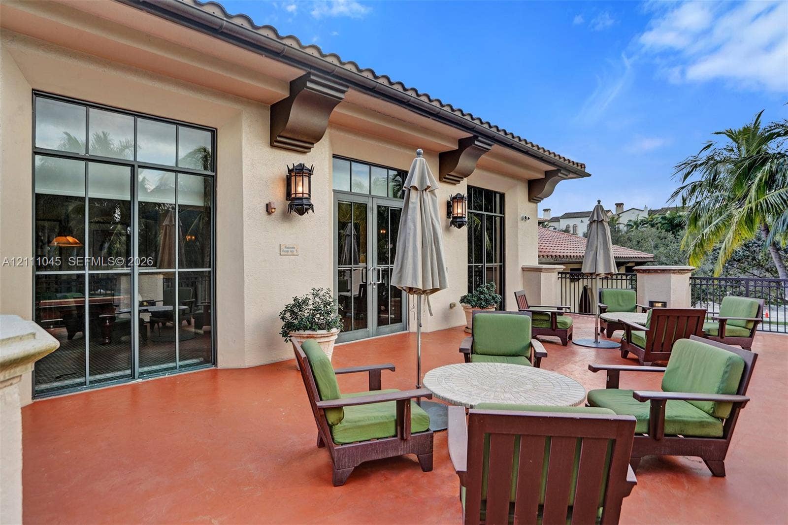 2901 NW 126th Avenue, #2-225, Sunrise, FL 33323 Covered outdoor terrace featuring terracotta-toned hardscaping, decorative corbels, black-framed French doors, and wall-mounted exterior lanterns