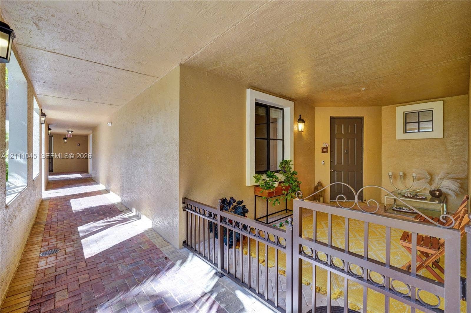 2901 NW 126th Avenue, #2-225, Sunrise, FL 33323 Covered entryway featuring brick pavers, decorative metal fencing, recessed lighting, and a paneled entry door