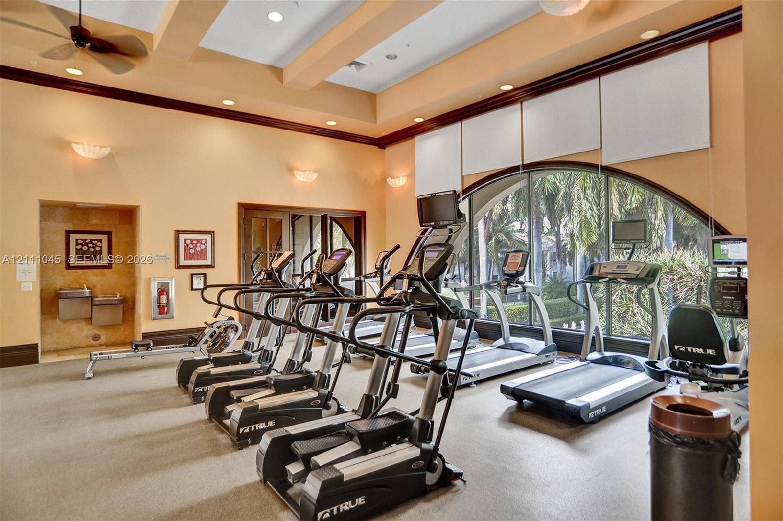 2901 NW 126th Avenue, #2-225, Sunrise, FL 33323 Fitness center featuring high ceilings with recessed lighting, an expansive arched window, integrated sound system, and wall-mounted water fountain