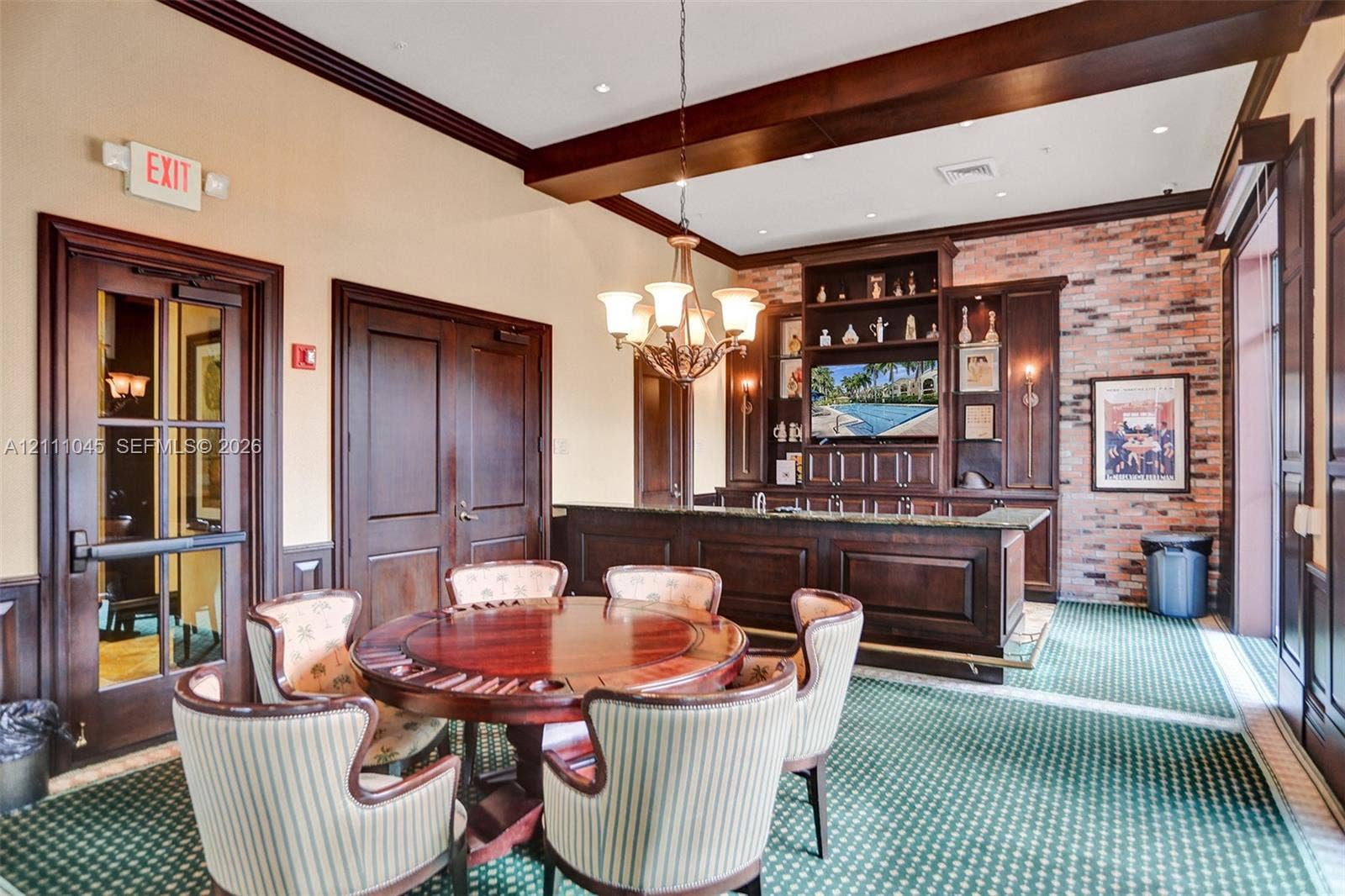 2901 NW 126th Avenue, #2-225, Sunrise, FL 33323 Custom built-in bar featuring dark wood cabinetry, exposed brick wall, overhead chandelier lighting, and dark wood crown molding