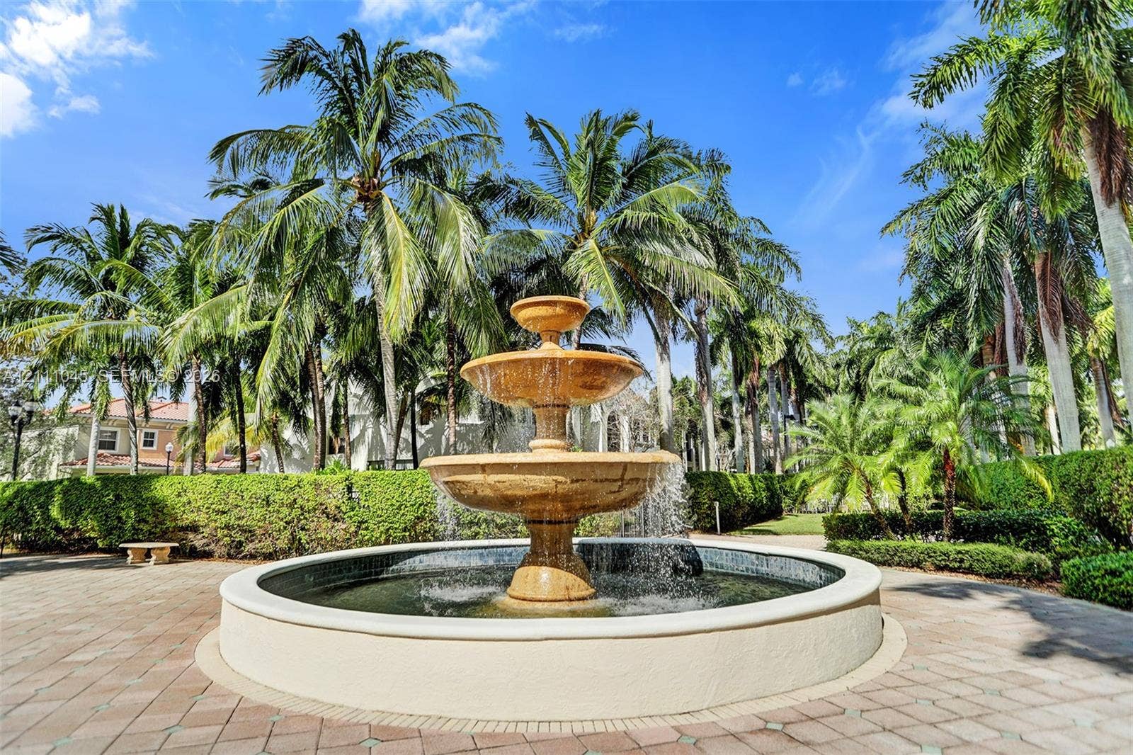 2901 NW 126th Avenue, #2-225, Sunrise, FL 33323 Three-tiered stone fountain centerpiece, circular paved plaza, and lush perimeter hedges framed by mature palm trees