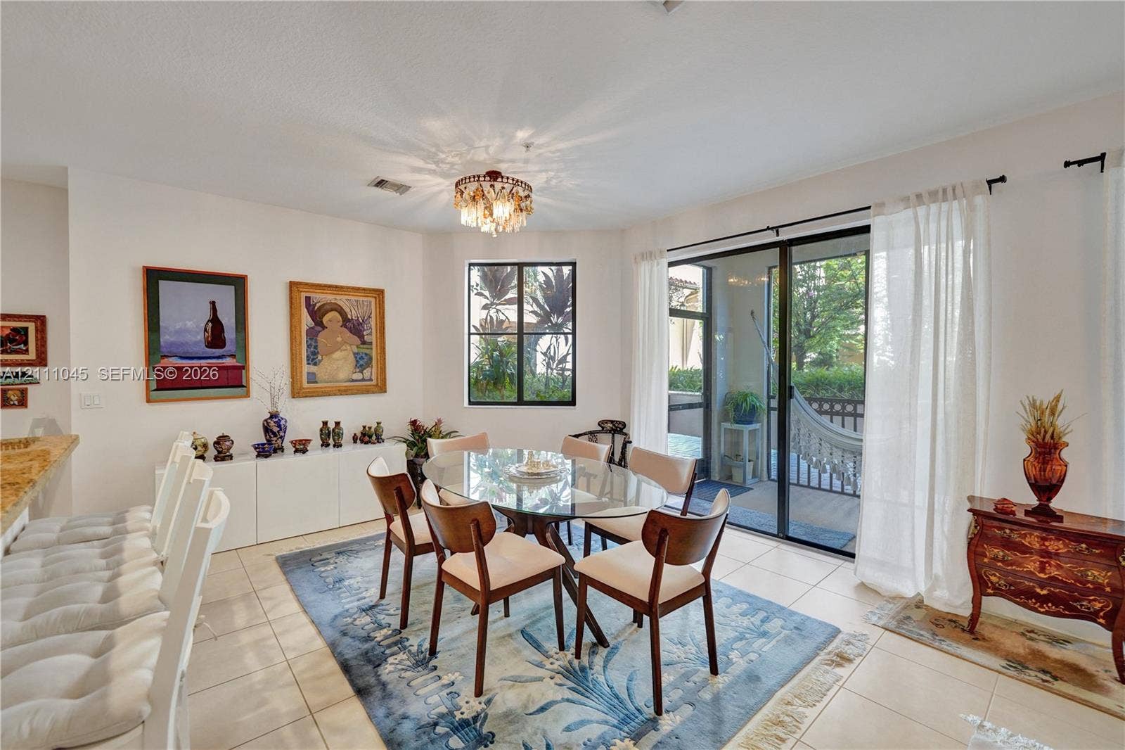 2901 NW 126th Avenue, #2-225, Sunrise, FL 33323 Dining area featuring large-format ceramic tile flooring, built-in cabinetry with a stone countertop, a decorative tiered chandelier, and sliding glass doors with access to a screened outdoor area