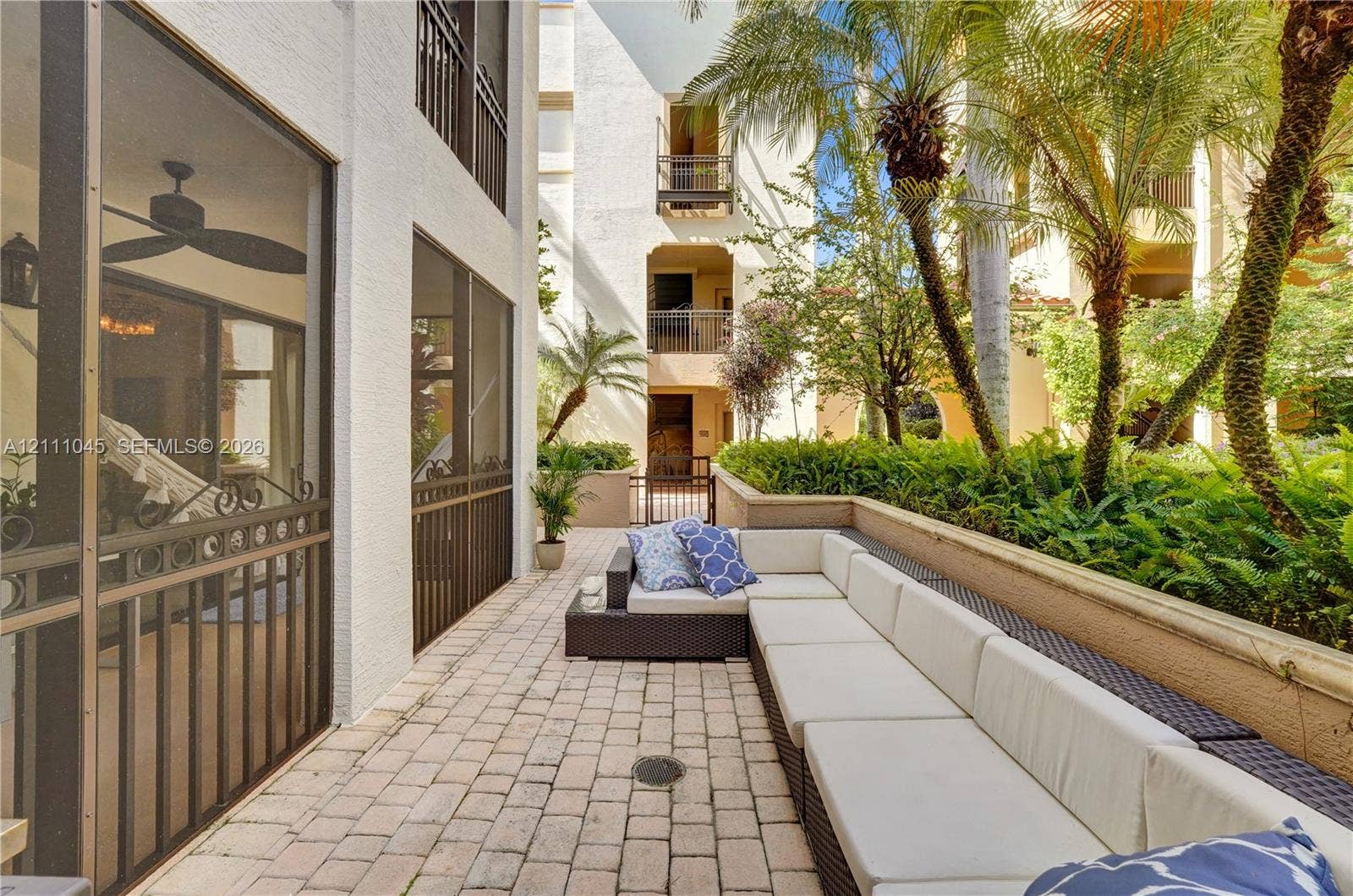 2901 NW 126th Avenue, #2-225, Sunrise, FL 33323 Paver-stone patio featuring a low masonry perimeter wall, screened-in enclosure, and integrated tropical landscaping