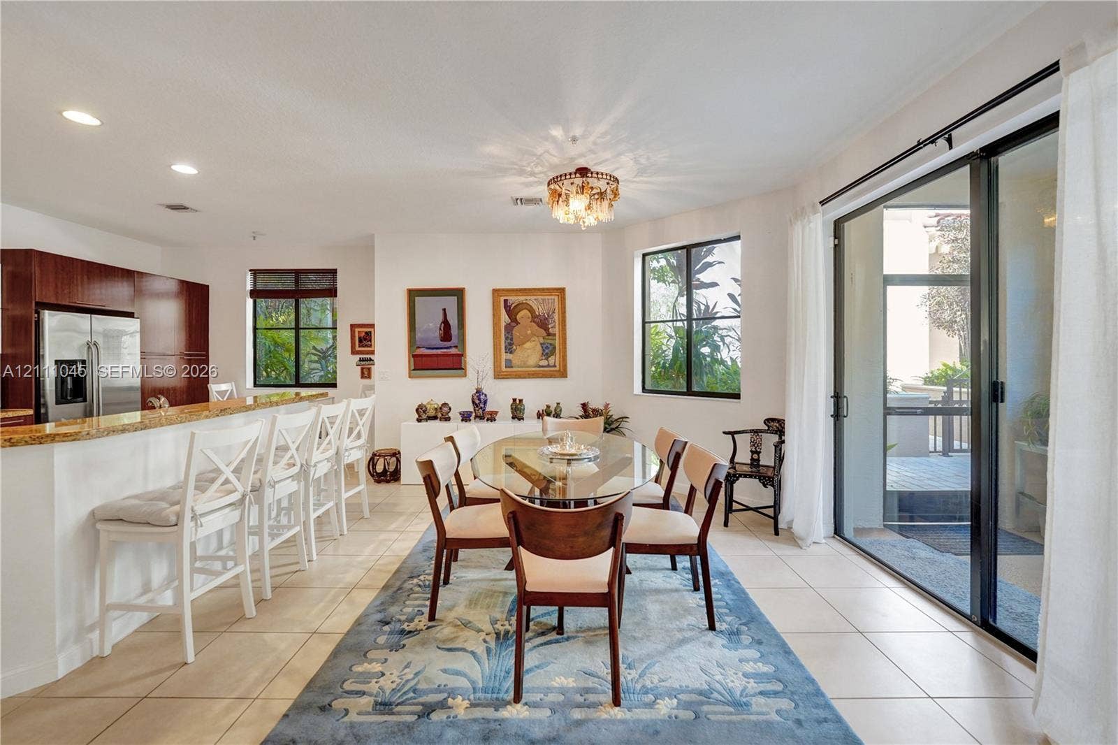 2901 NW 126th Avenue, #2-225, Sunrise, FL 33323 Open-concept kitchen and dining area featuring a tiered stone-top breakfast bar, tile flooring, recessed lighting, and large sliding glass doors