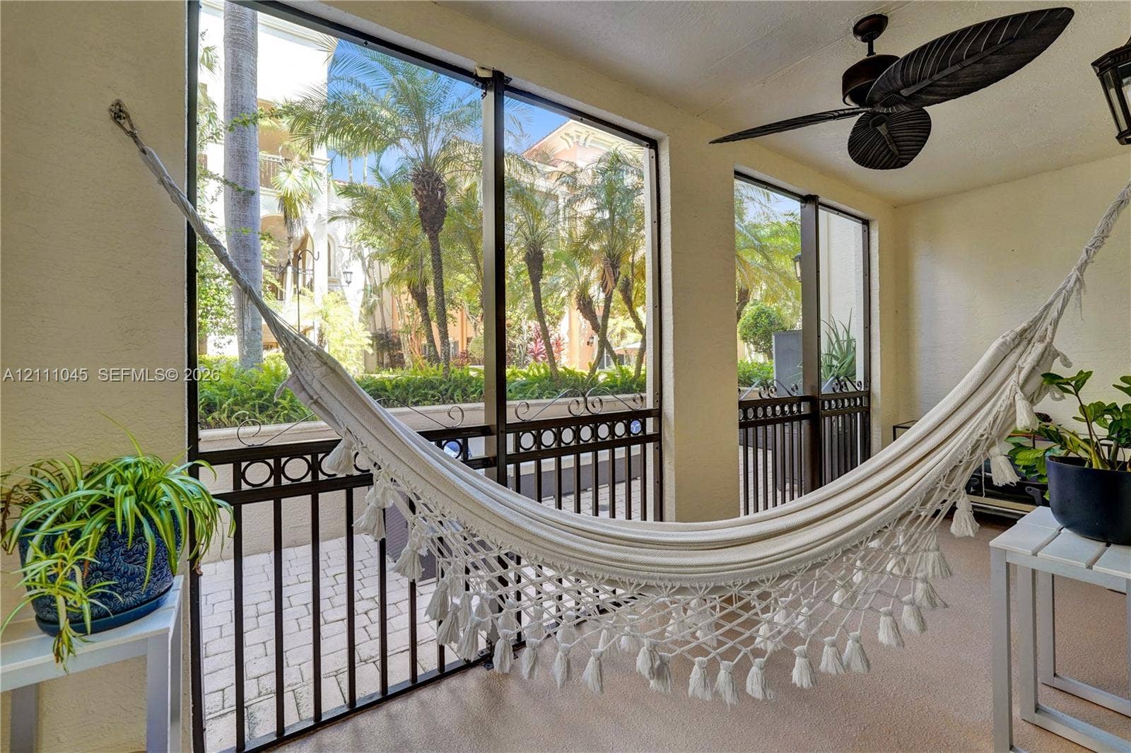 2901 NW 126th Avenue, #2-225, Sunrise, FL 33323 Screened-in porch featuring full-height window panels, black metal decorative railings, and a ceiling-mounted fan