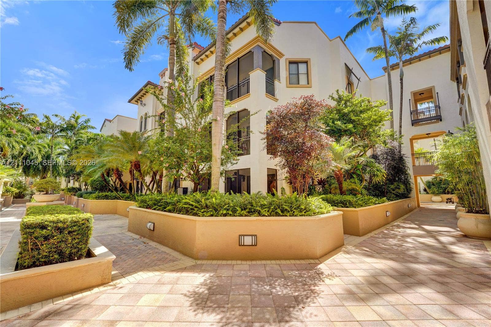 2901 NW 126th Avenue, #2-225, Sunrise, FL 33323 Mediterranean-style exterior featuring stucco facade, multi-level screened balconies, paver walkways, integrated landscape lighting, and raised masonry planters