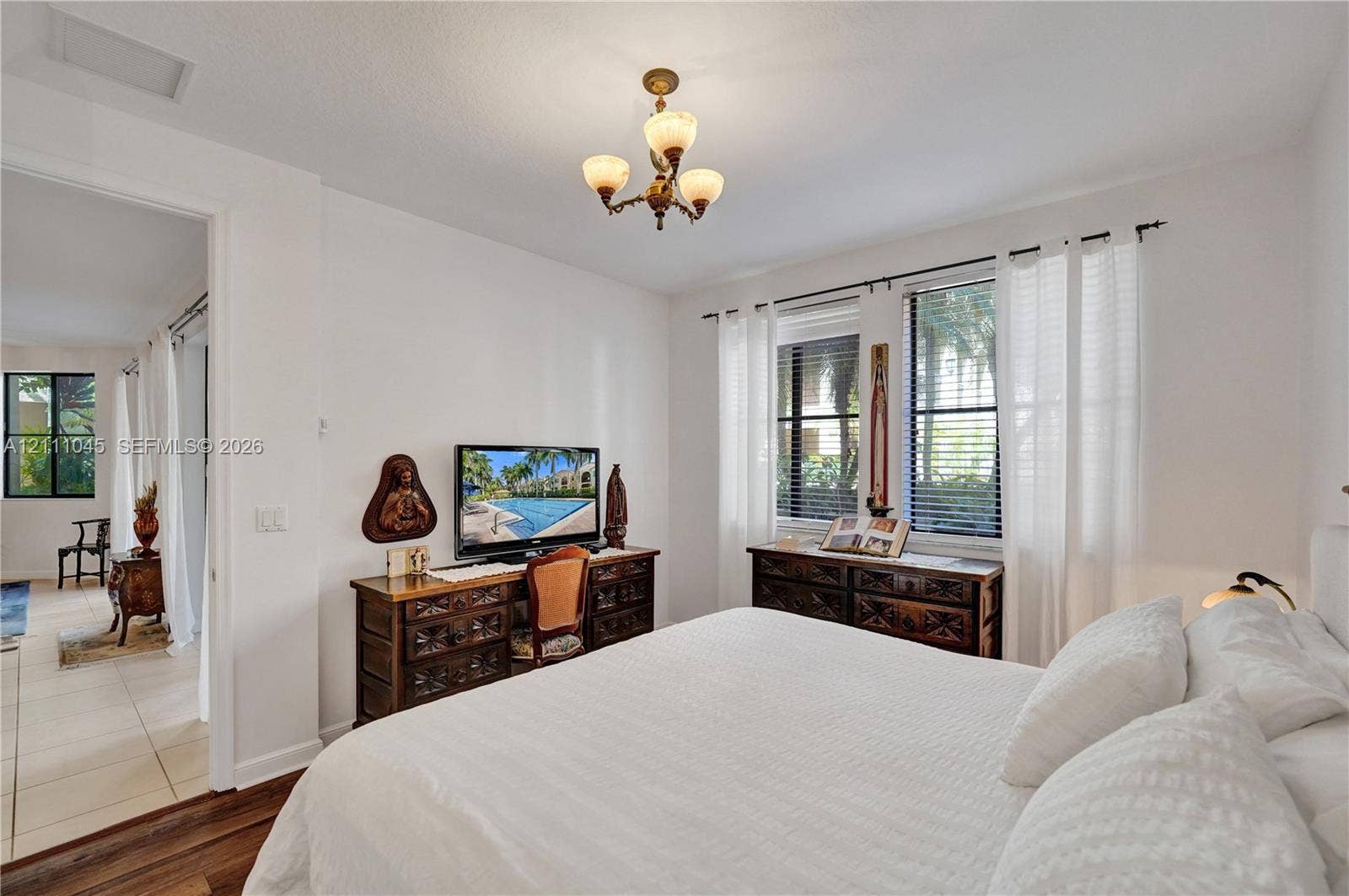2901 NW 126th Avenue, #2-225, Sunrise, FL 33323 Interior space featuring three-light chandelier, dual windows with horizontal blinds, and wood-finish flooring