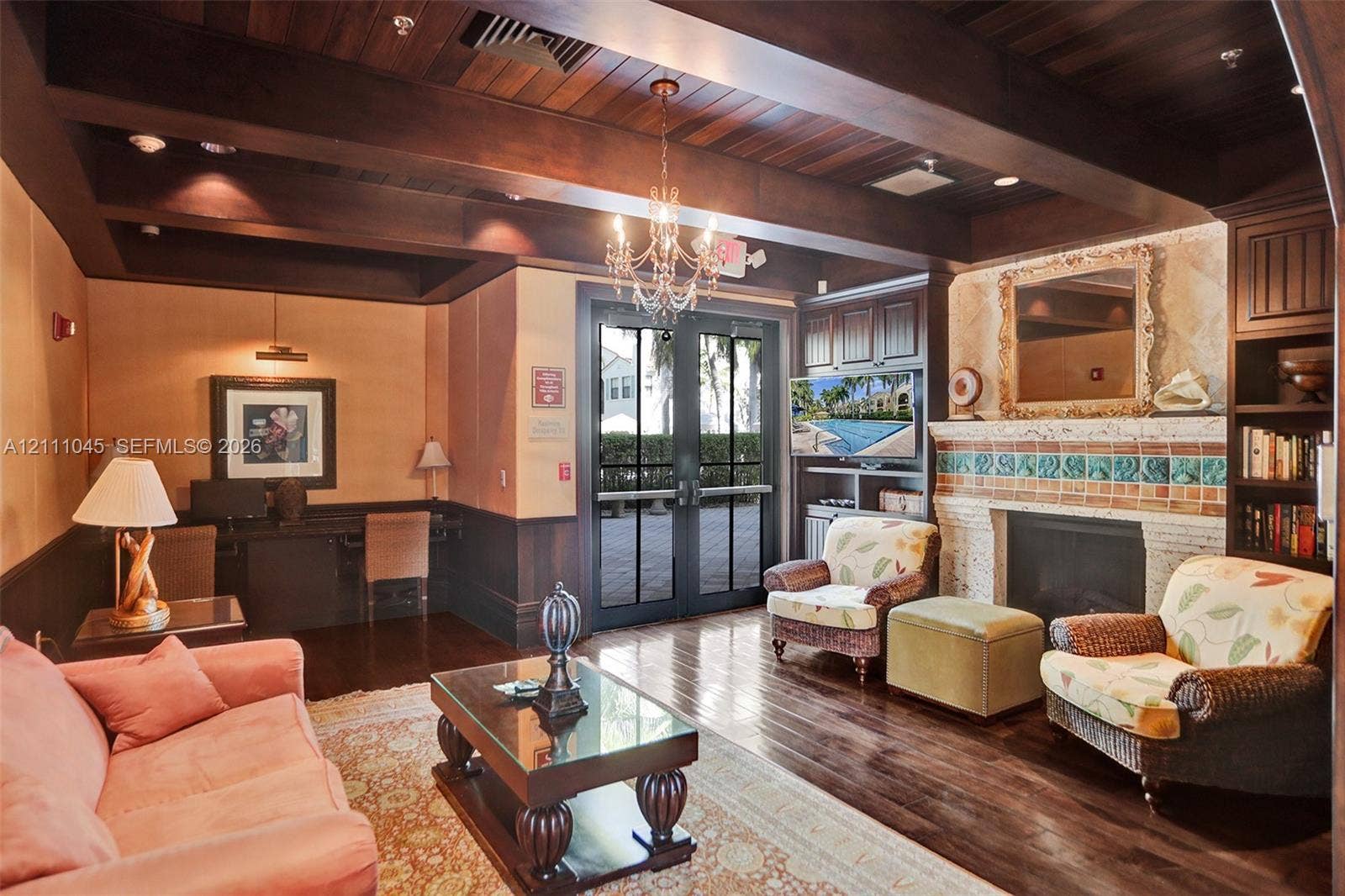 2901 NW 126th Avenue, #2-225, Sunrise, FL 33323 Wood-finish coffered ceiling with exposed beams, wood-finish flooring, masonry fireplace with decorative tile surround, built-in wooden cabinetry, and French-style glass paneled doors
