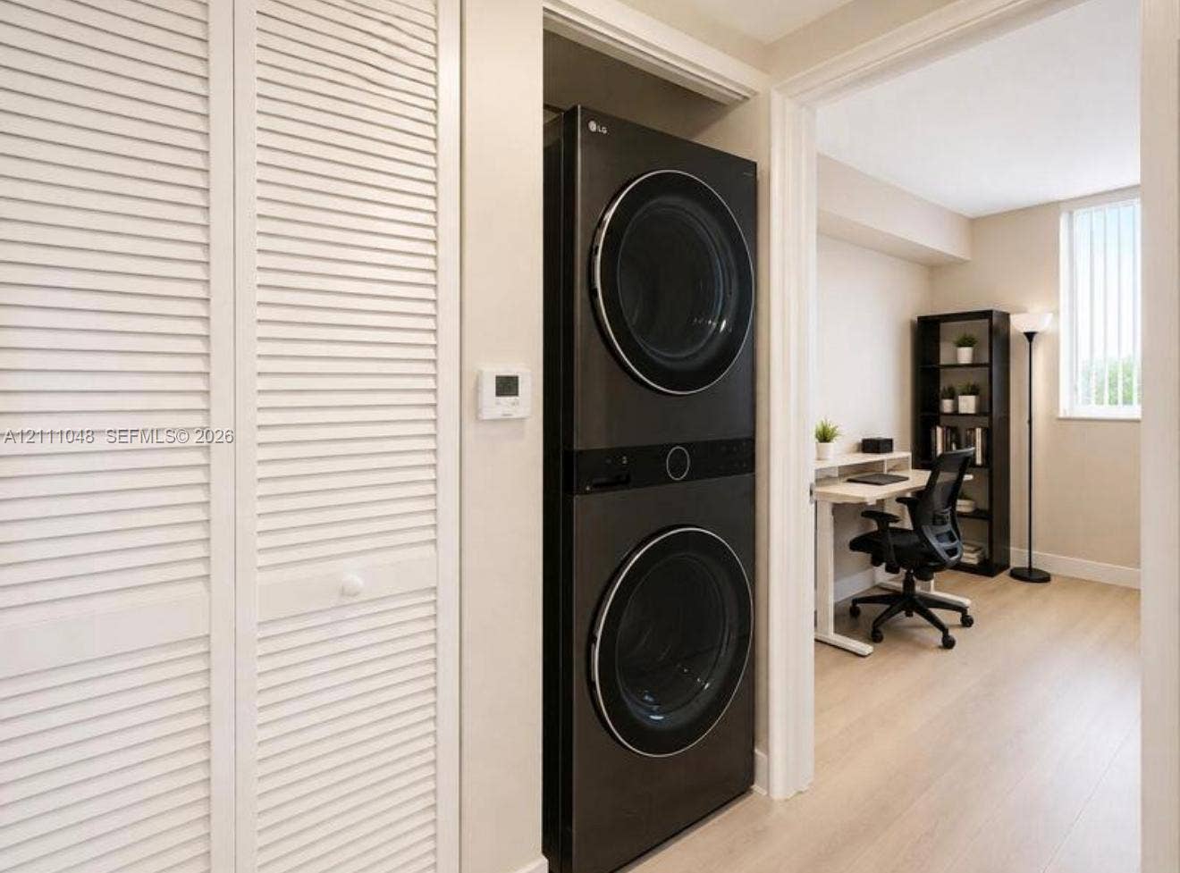 2775 NE 187th Street, #408, Aventura, Aventura, FL 33180 Integrated laundry closet featuring a stacked washer and dryer unit, louvered bi-fold doors, and wood-finish flooring