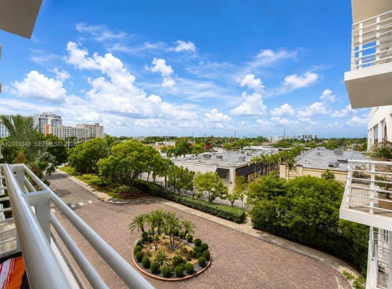 2775 NE 187th Street, #408, Aventura, Aventura, FL 33180 Elevated balcony with white metal railings overlooking a paved circular drive featuring manicured landscaping and mature trees