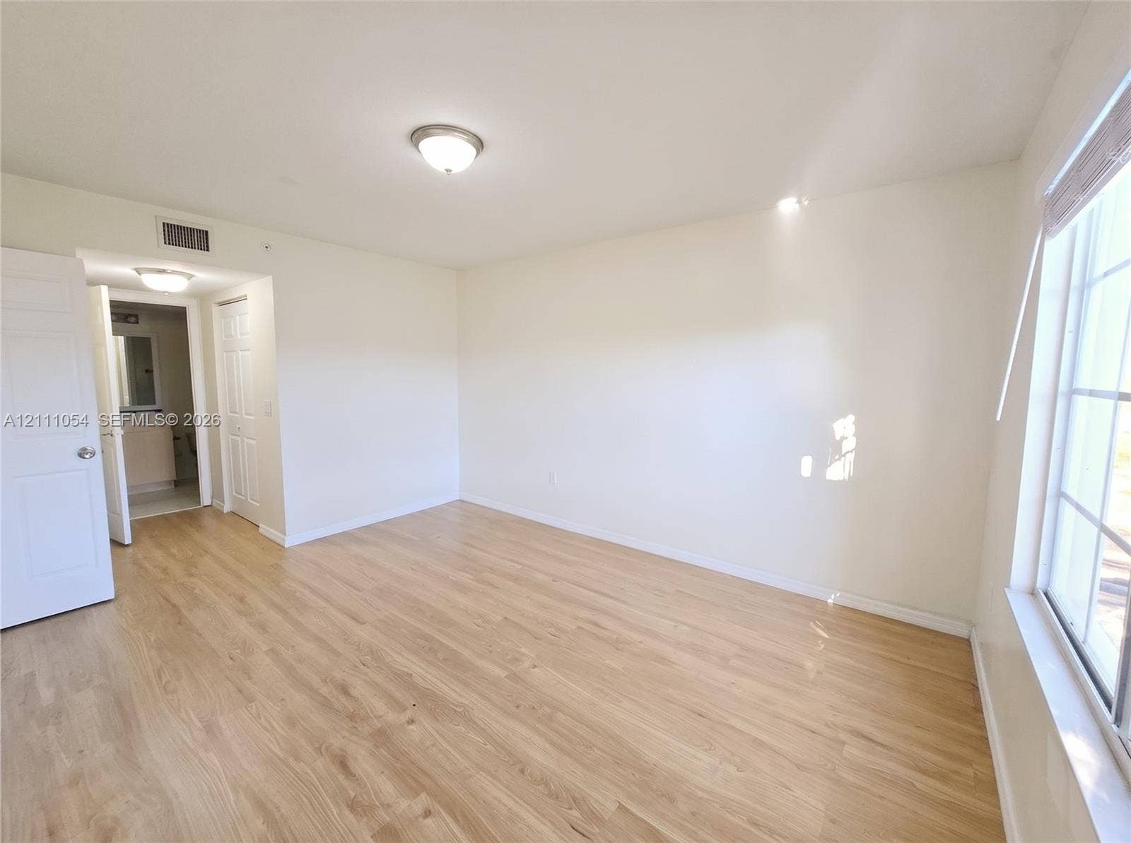 4180 San Marino Boulevard, #106, West Palm Beach, FL 33409 Room featuring wood-finish flooring, multi-pane windows, flush-mount ceiling lighting, and panel doors