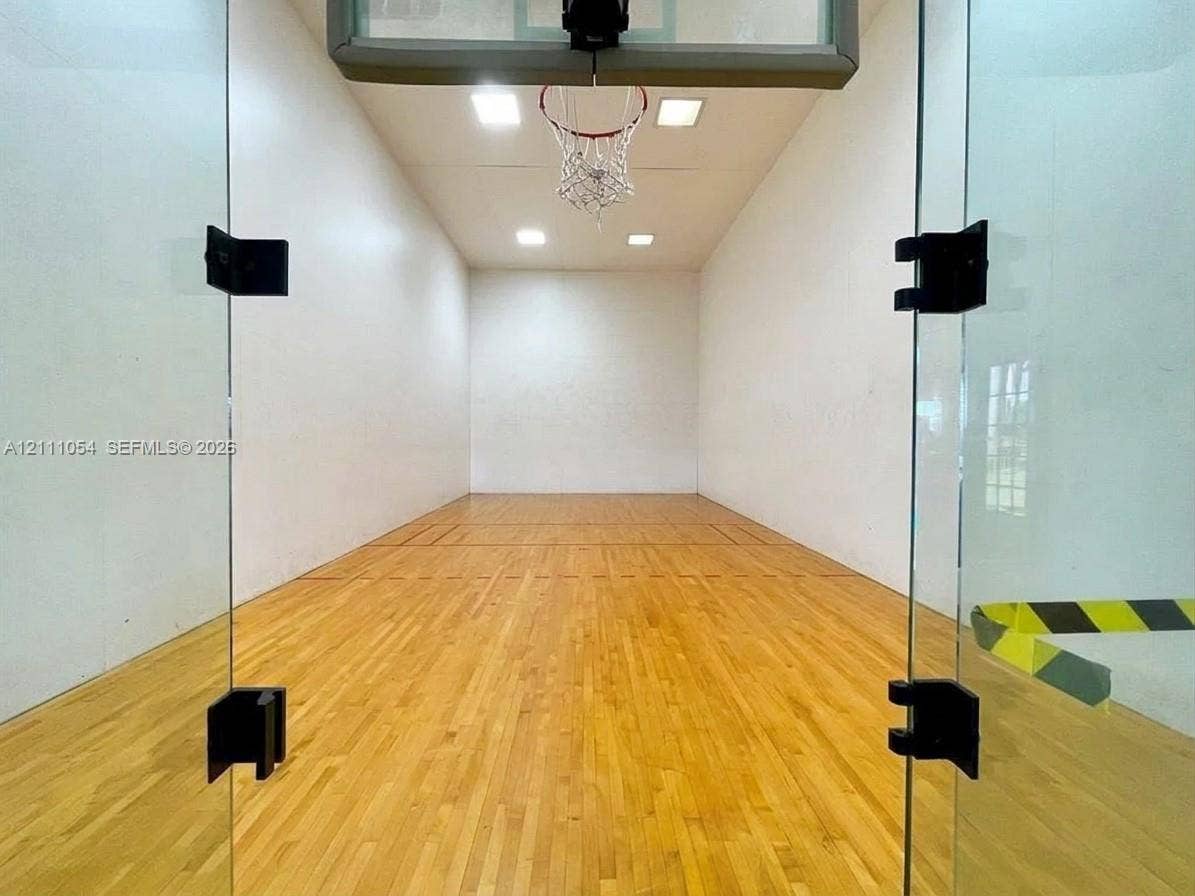 4180 San Marino Boulevard, #106, West Palm Beach, FL 33409 Recreational court featuring wood-finish flooring, glass enclosure, recessed ceiling lighting, and a wall-mounted basketball hoop