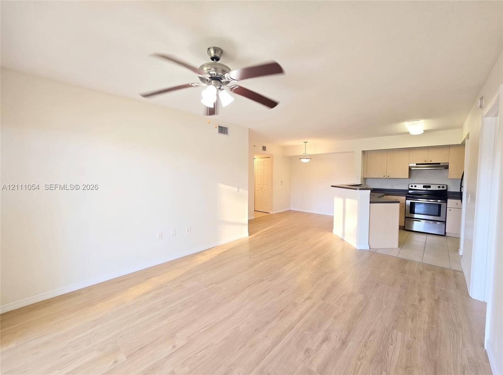 4180 San Marino Boulevard, #106, West Palm Beach, FL 33409 Wood-finish flooring, ceiling fan with integrated lighting, kitchen featuring a breakfast bar, flat-panel cabinetry, and stainless steel range